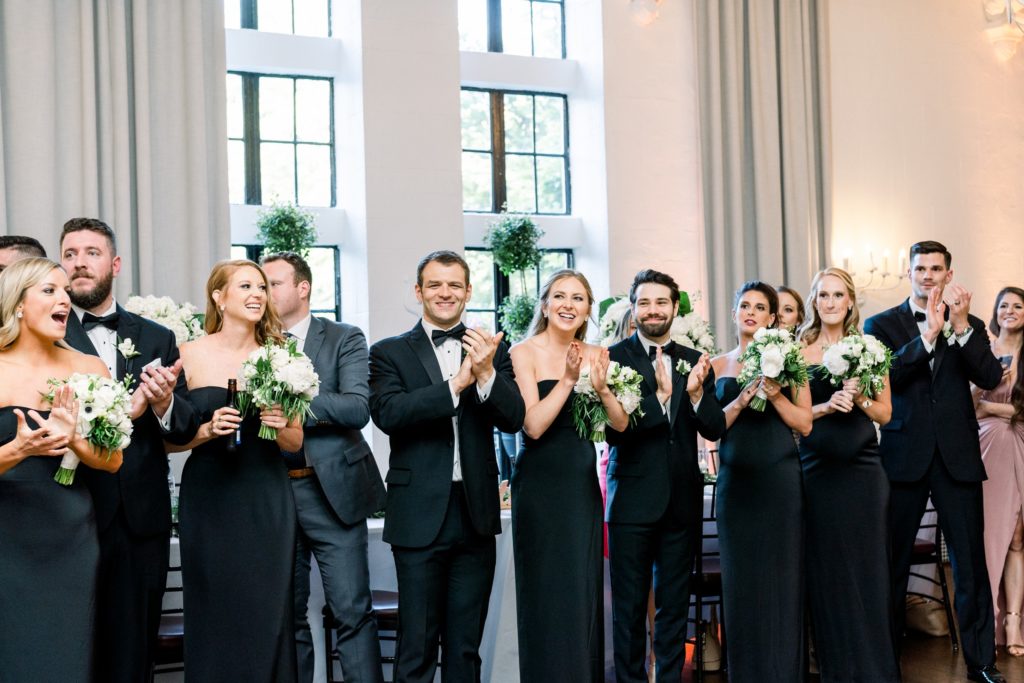 bridal party cheers as bride and groom enter reception