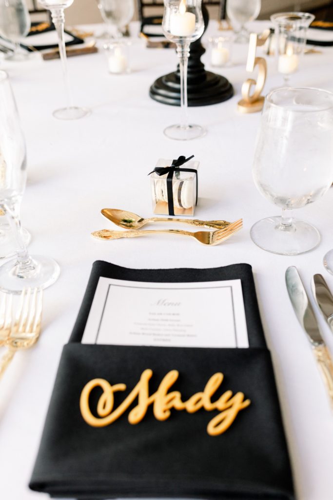 black napkins gold silverware gold acrylic name cutouts as escort cards and french macarons at alden castle wedding