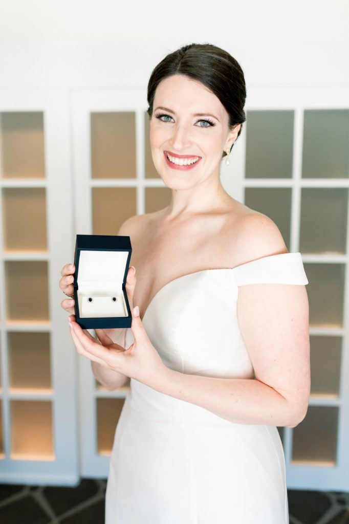 bride holding sapphire earrings from grooom on wedding day