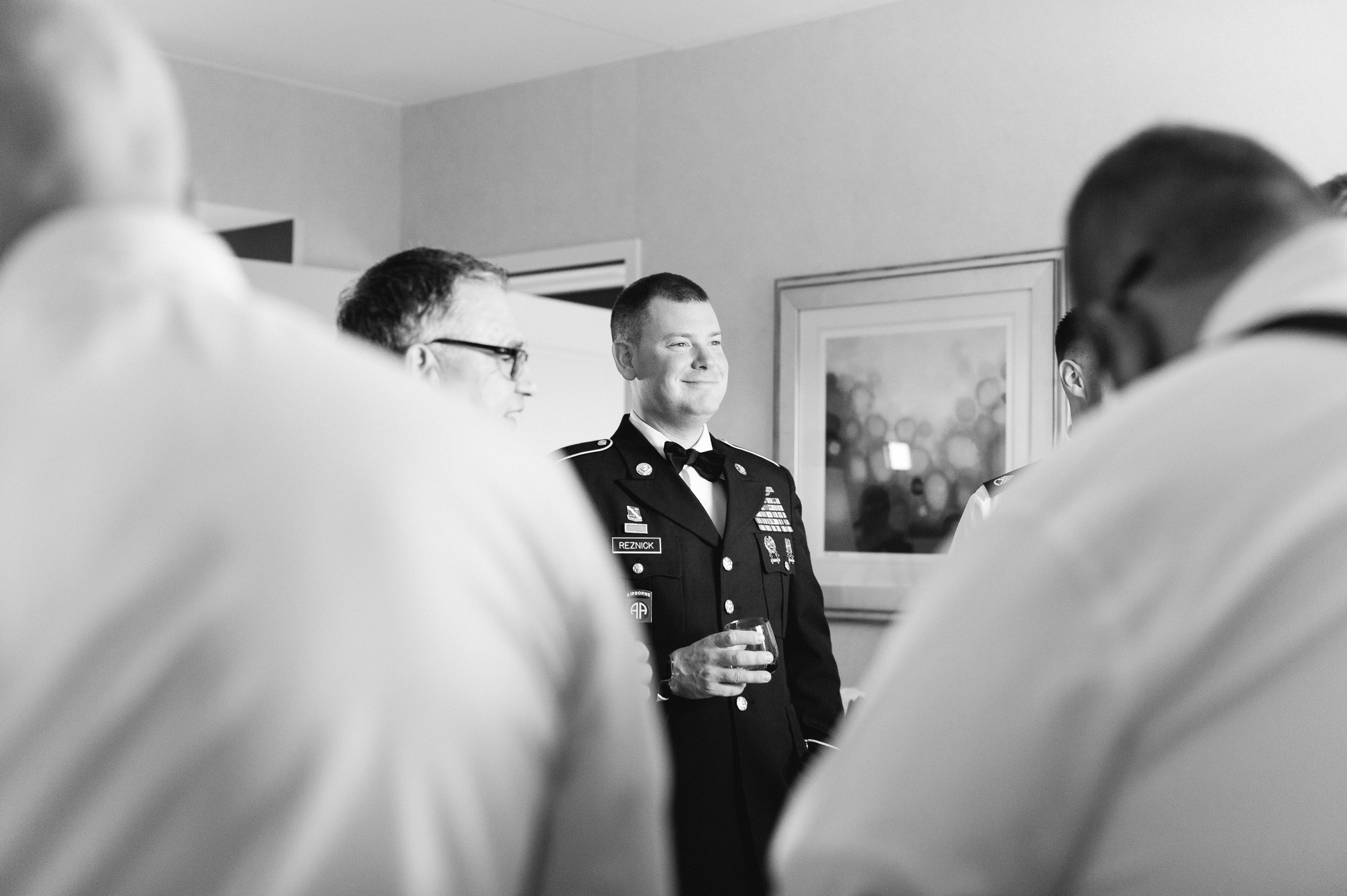 black and white photo military groom getting into uniform on wedding day