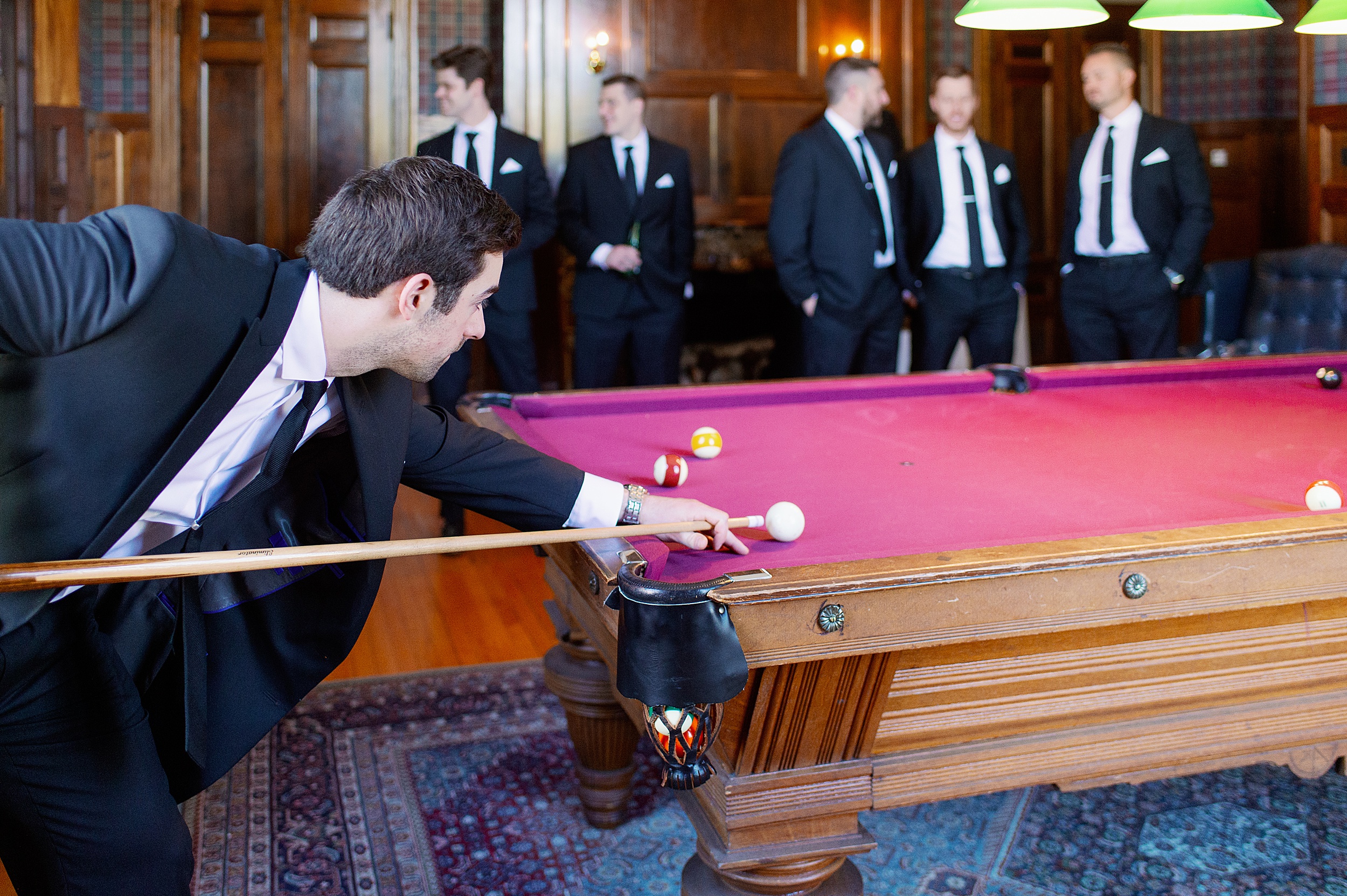 Groomsmen play pool while getting ready for estate wedding in Beverly MA