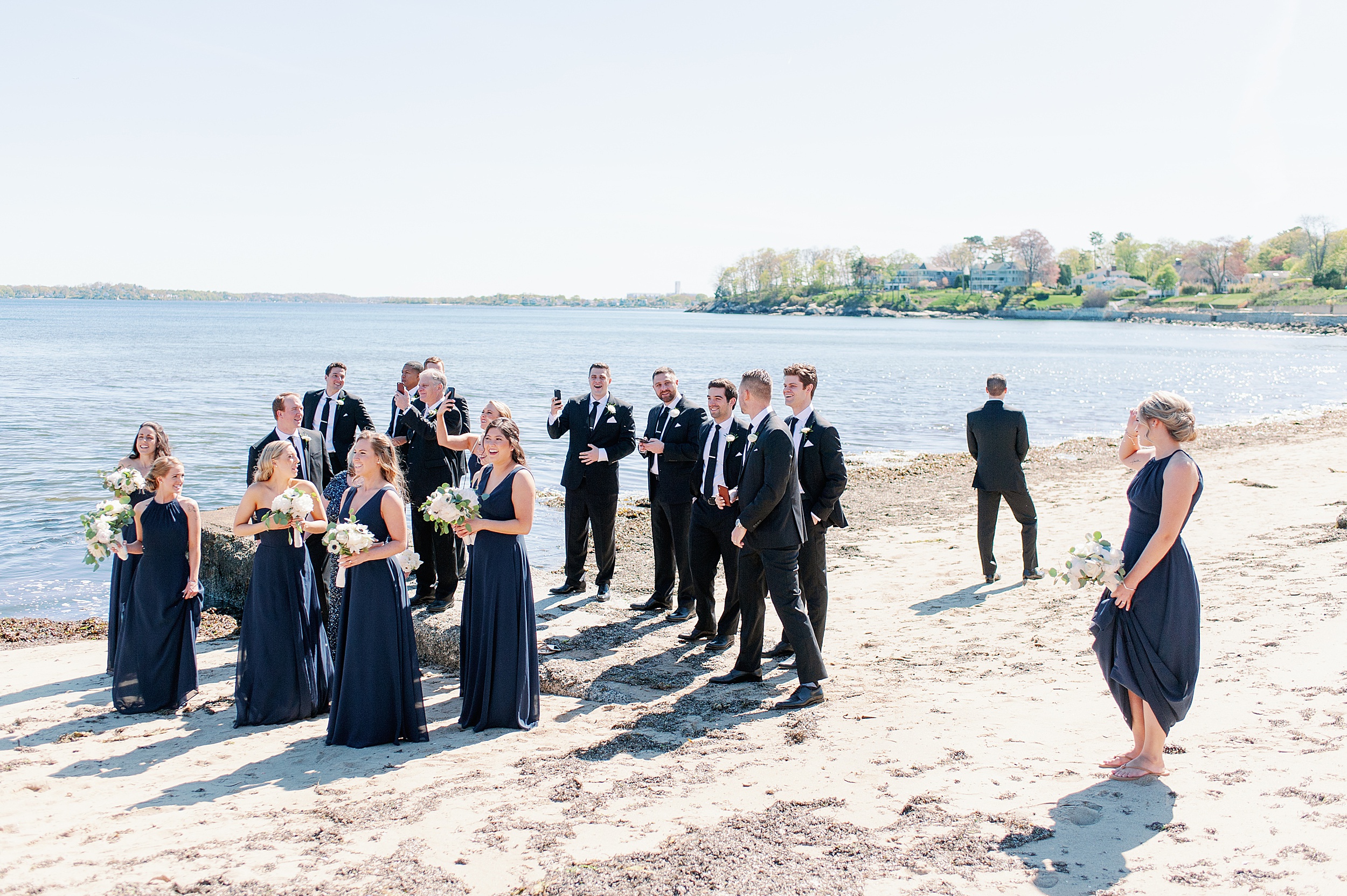 groom waits with bridal party for bride to arrive for first look on the beach
