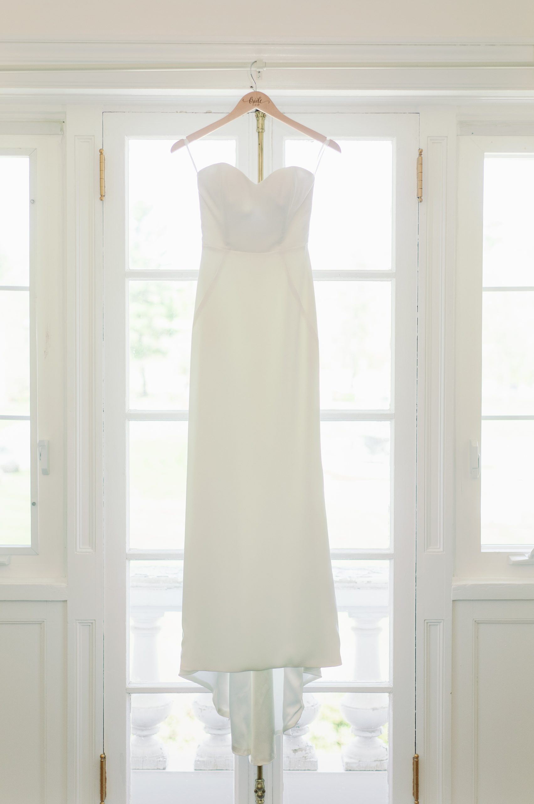 Wedding dress hung in window for estate wedding in Beverly MA North Shore Boston
