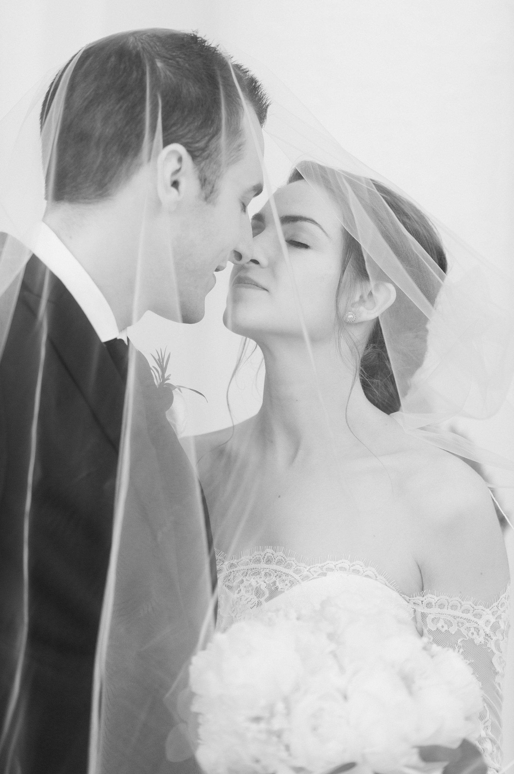 classic black and white portrait of bride and groom under veil