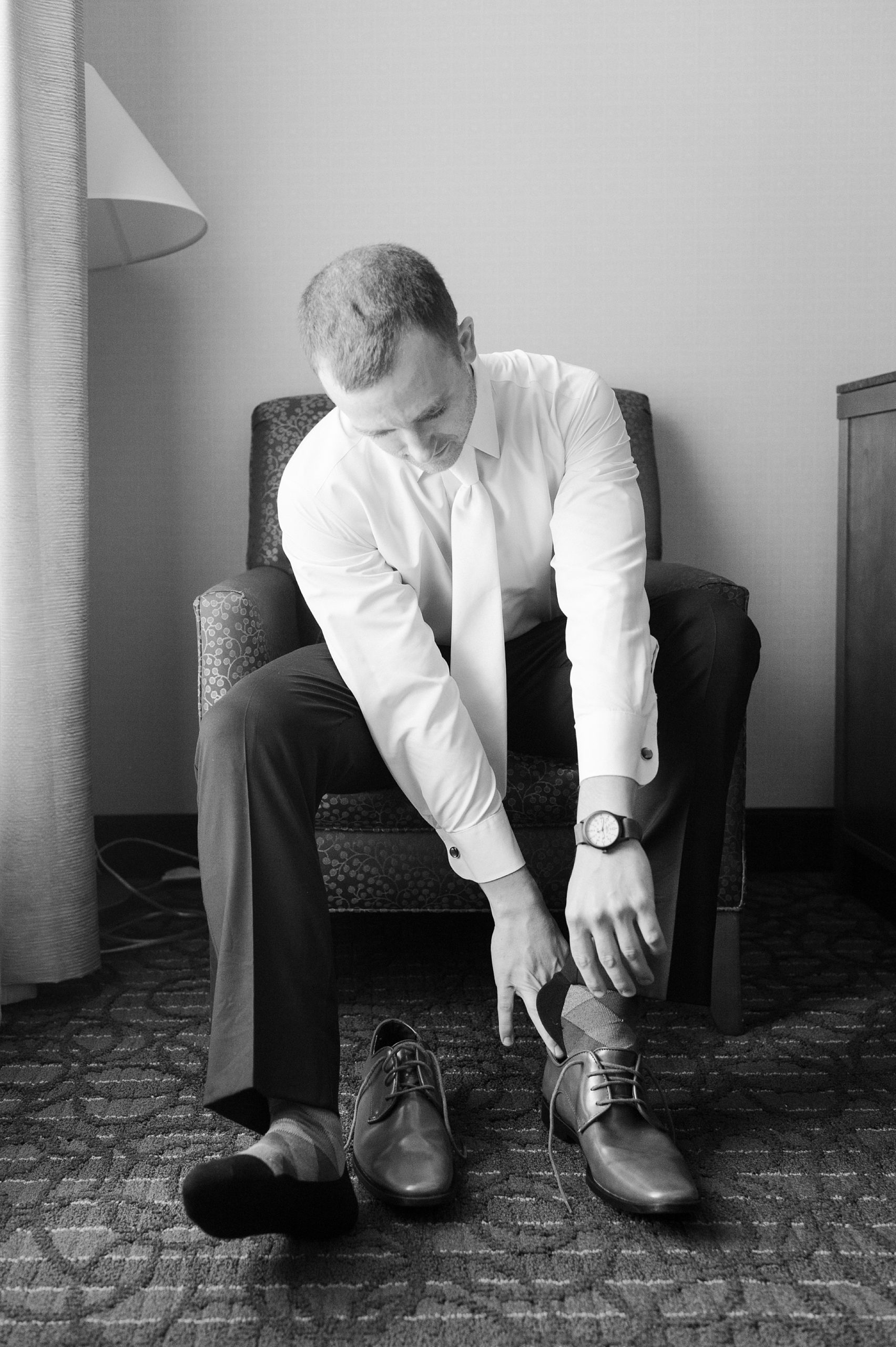 black and white of groom getting ready