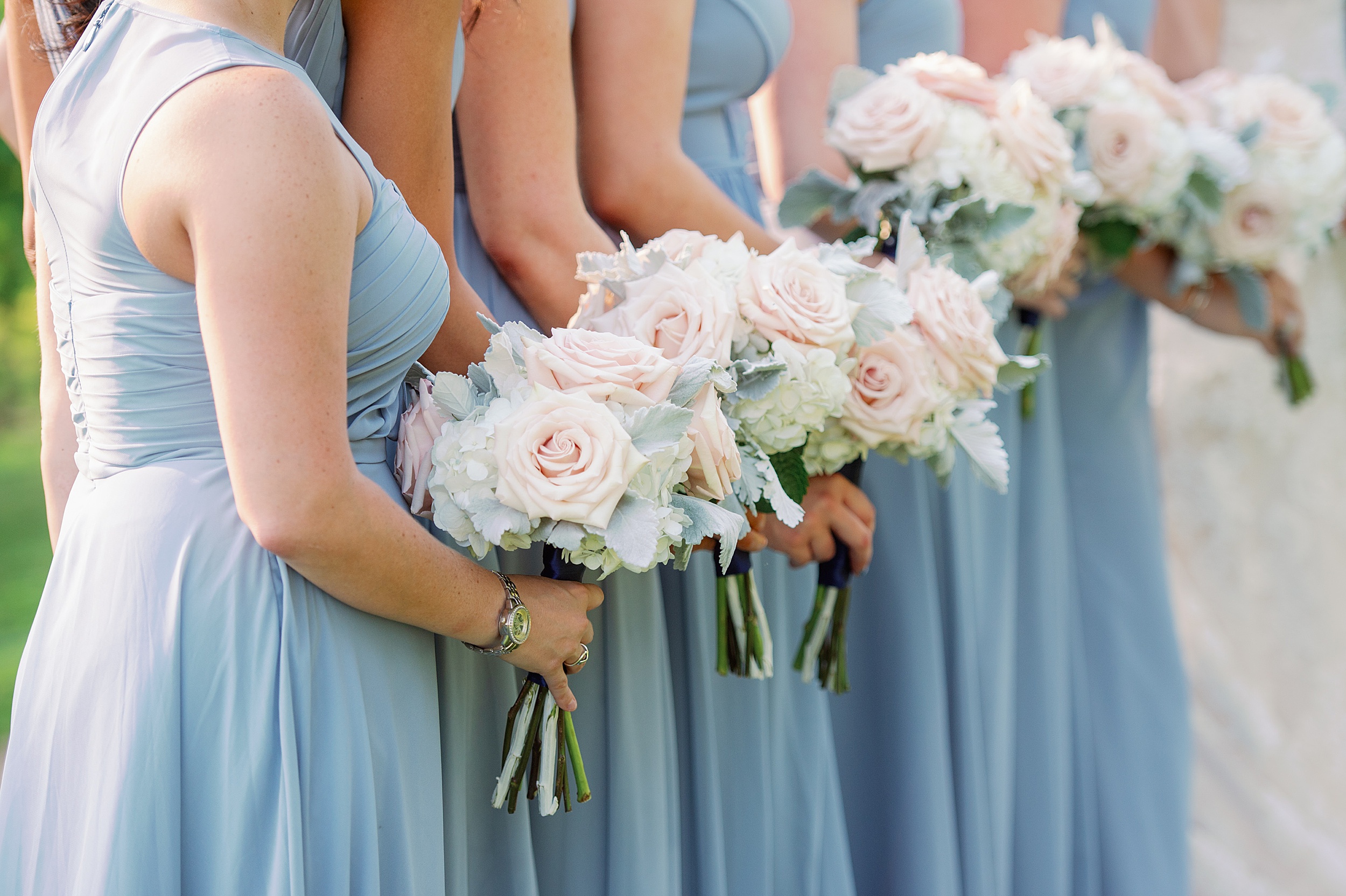 detail shot of blush and white flowers with pale blue bridesmaids dresses