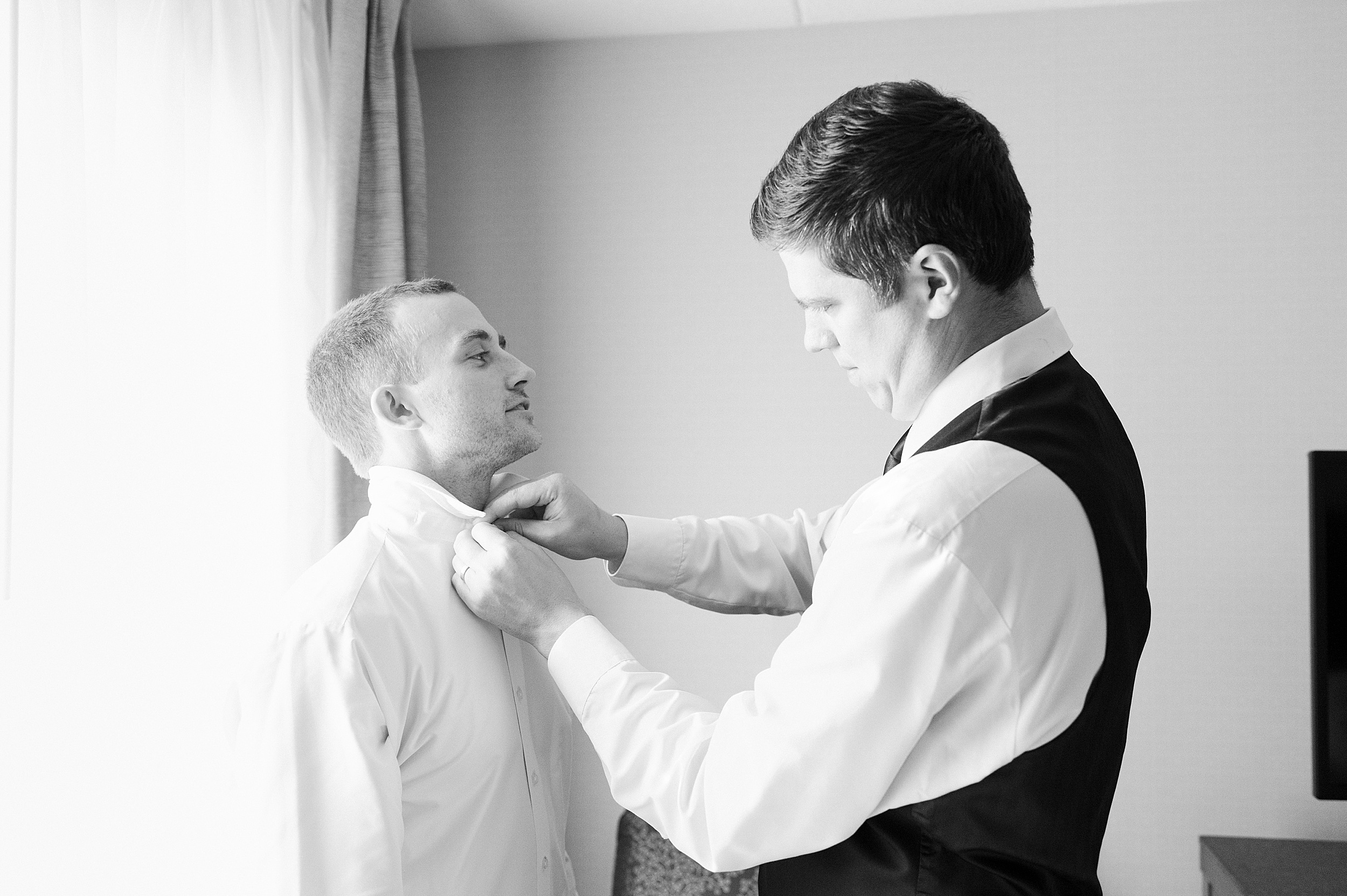 black and white of groom getting ready