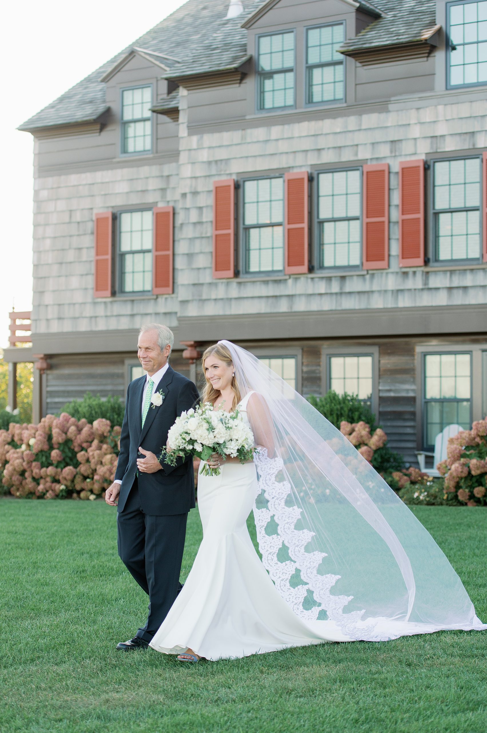 bride walks down the aisle with her dad in cathedral veil