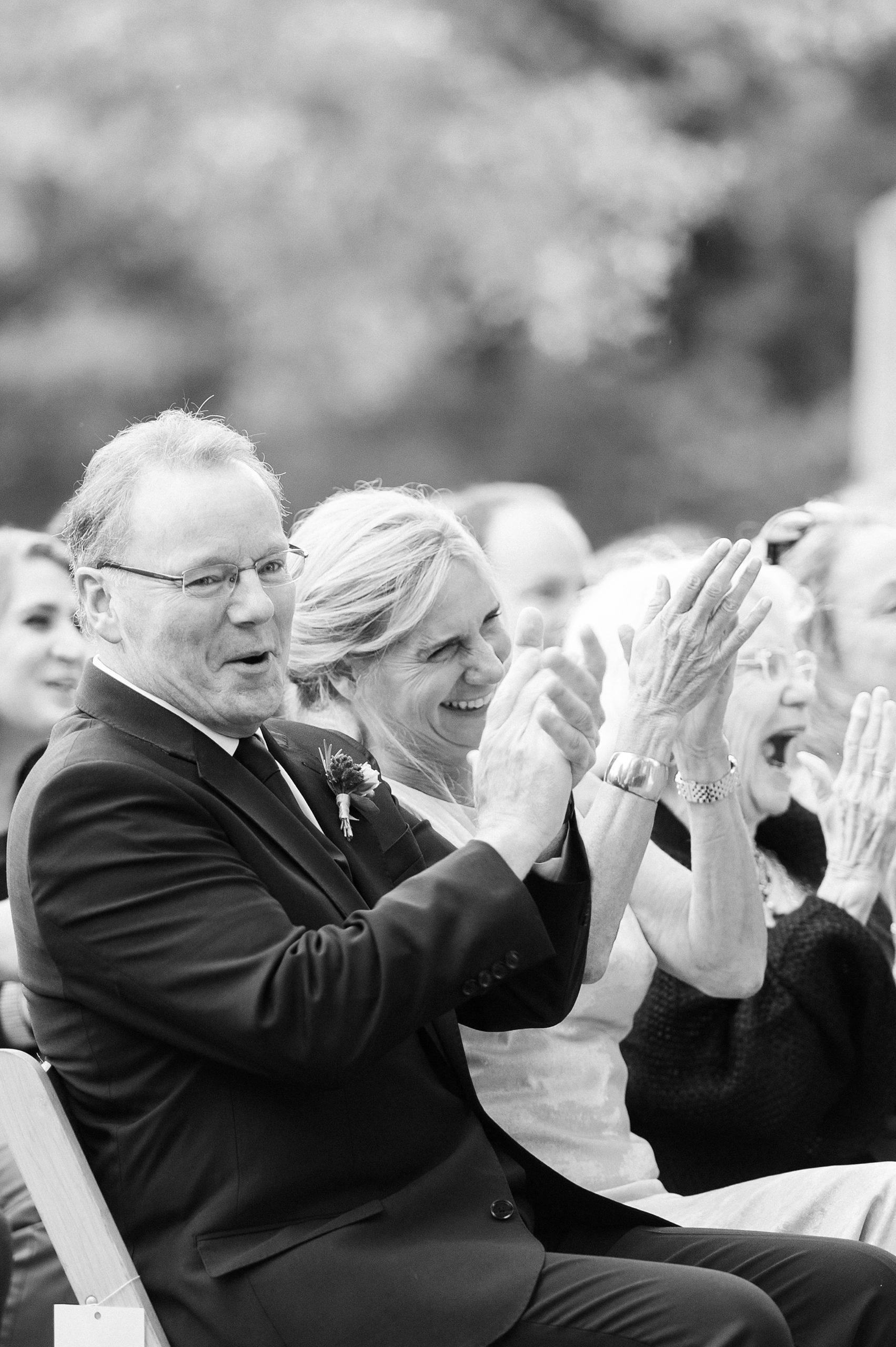 black and white of parents clapping during wedding ceremony