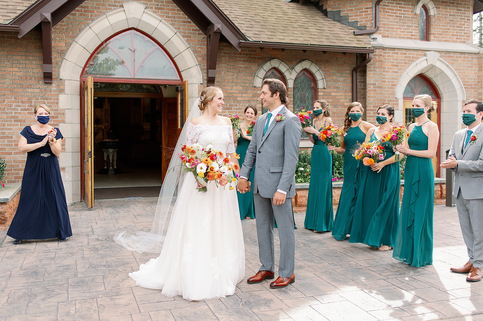 masked guests cheer as newlyweds exit church at Adirondack micro wedding
