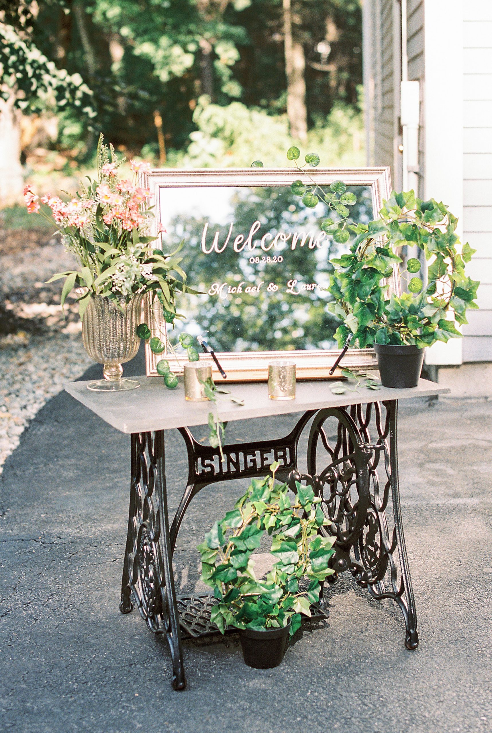 welcome sign on gilded mirror and vintage sewing table decorated with plants