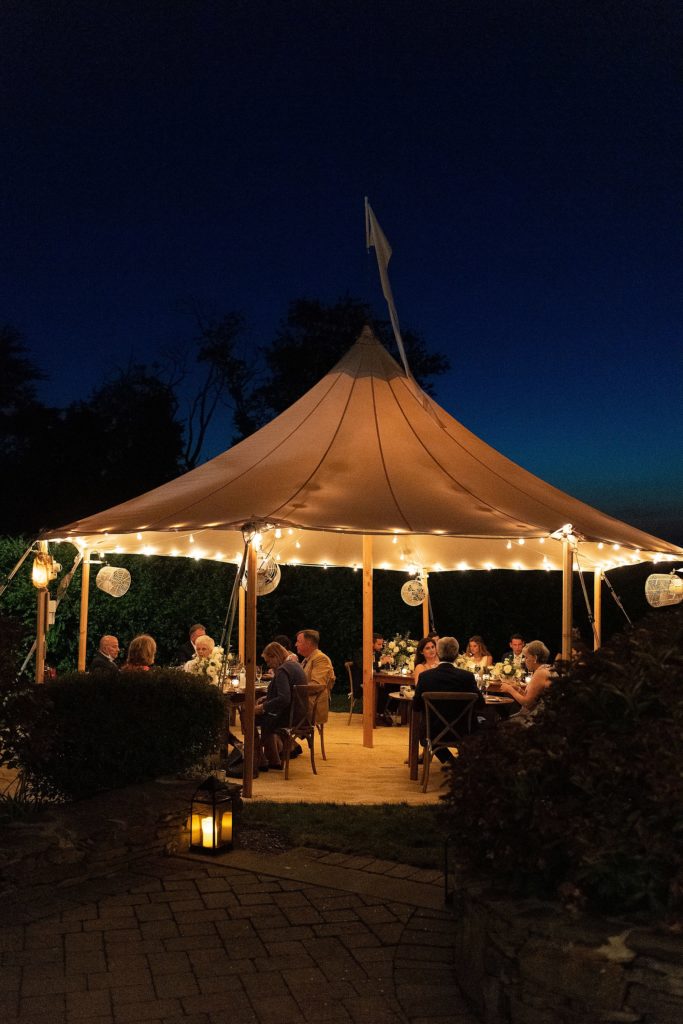 tiny sperry tent lit up at night for micro wedding reception on Cape Cod