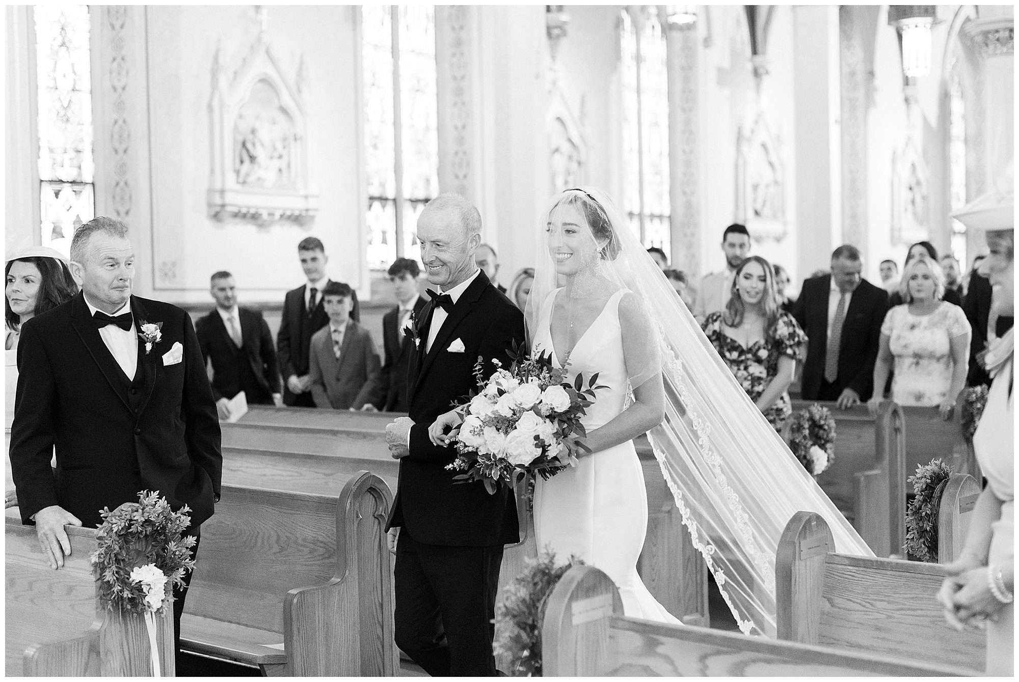 bride escorted down the aisle at saint gregory parish in dorchester black and white