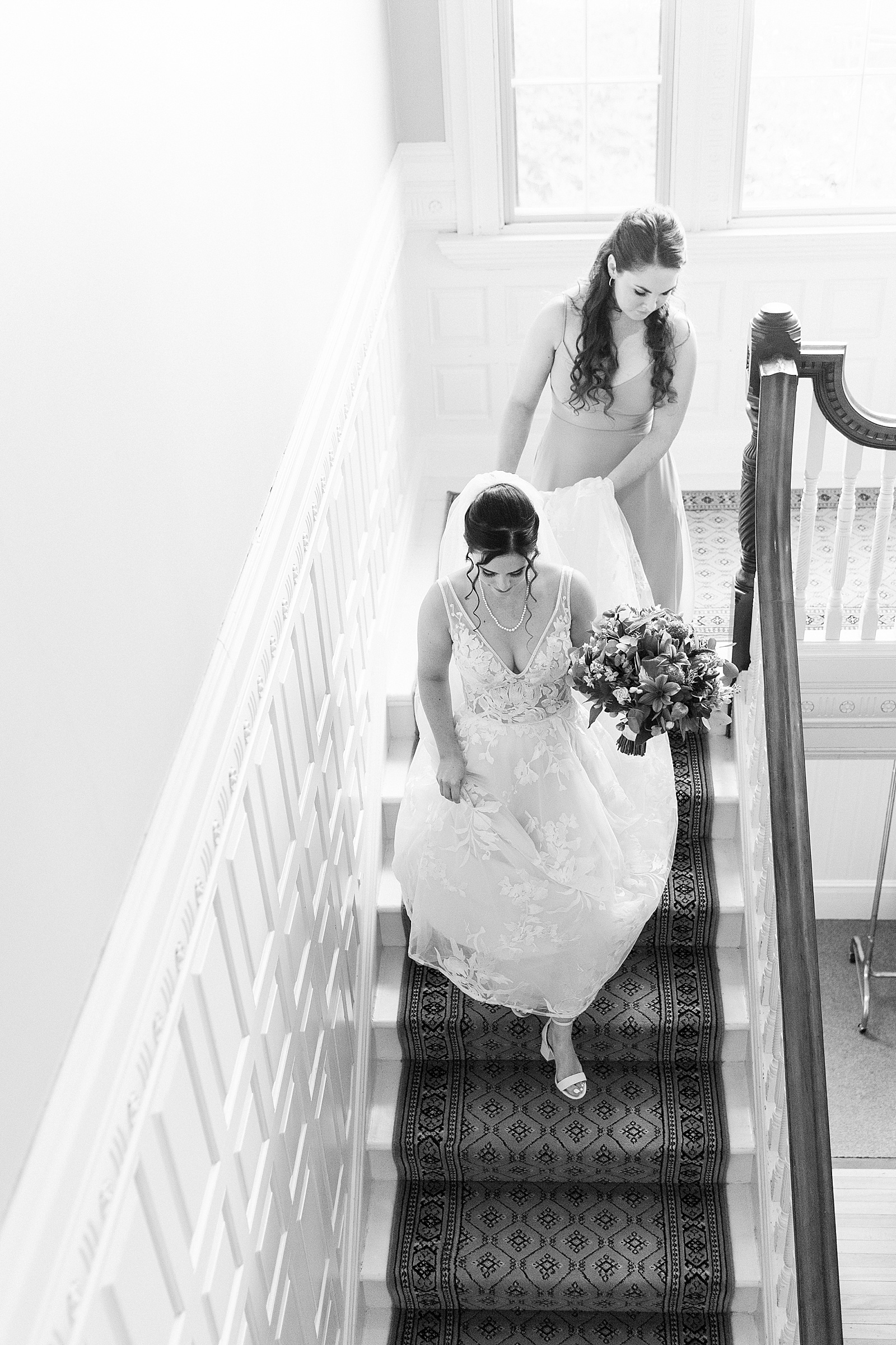 Black and white image of bride walking down the stairs. 