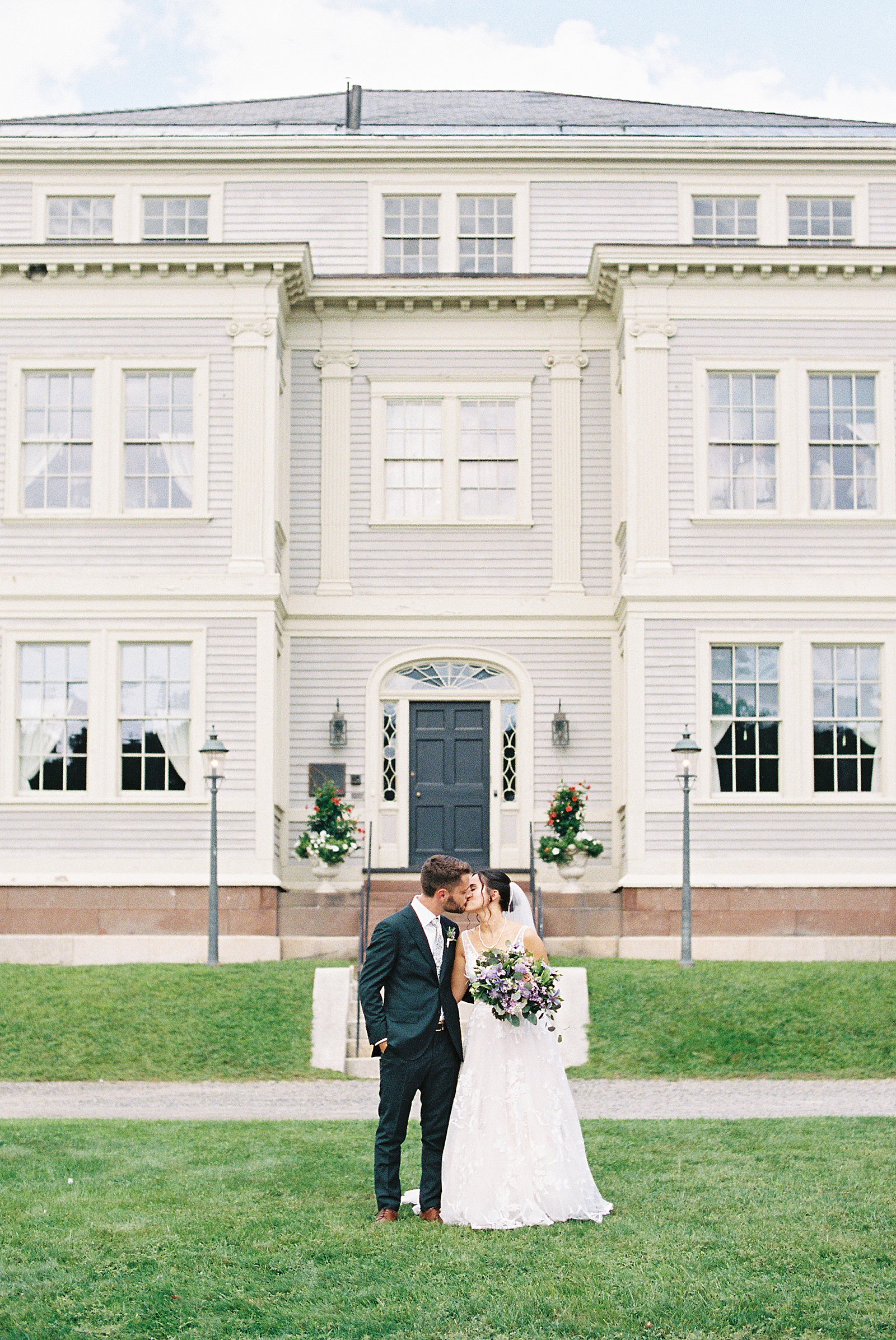 Bride and groom share a kiss in front of the Lyman Estate.