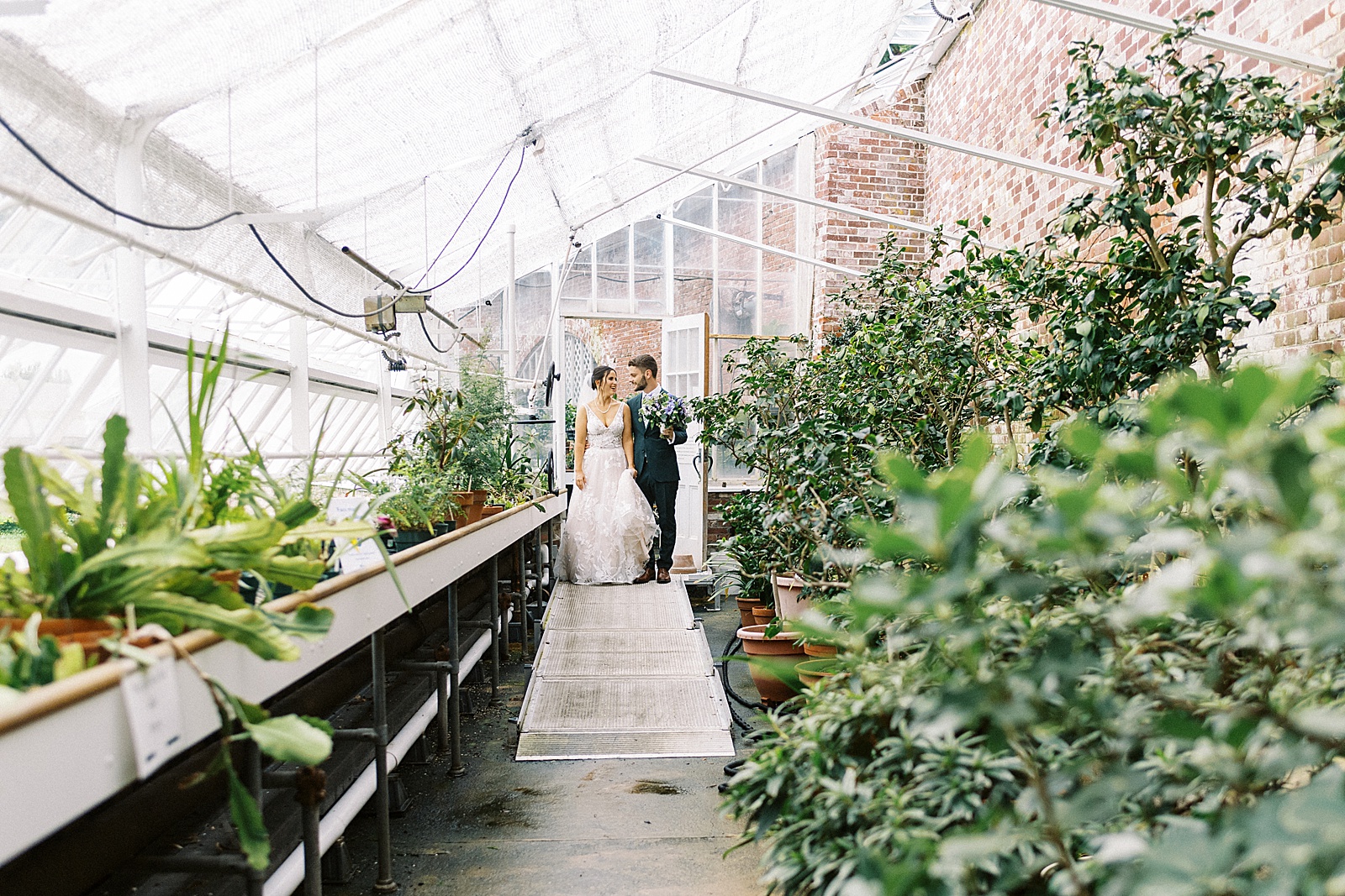 Bride and groom walking into a greenhouse together. 