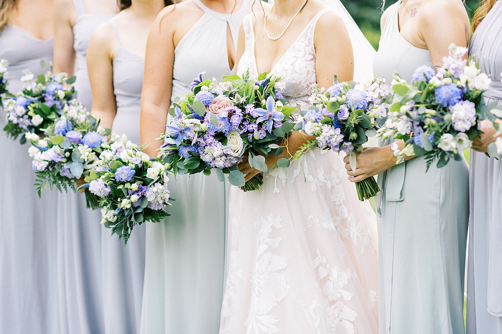 Up close of bride and her bridesmaids holding their lavender flowers. 