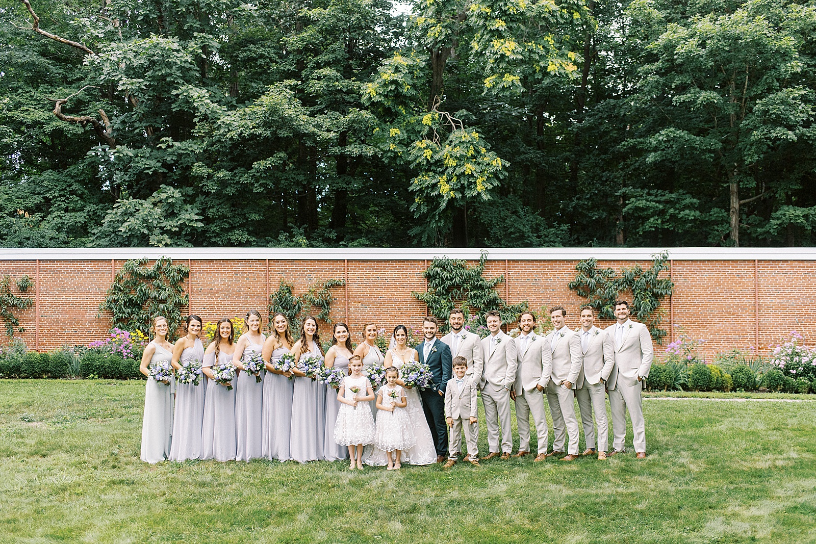 Bride and groom with their entire wedding party posing on the lawn at The Lyman Estate. 