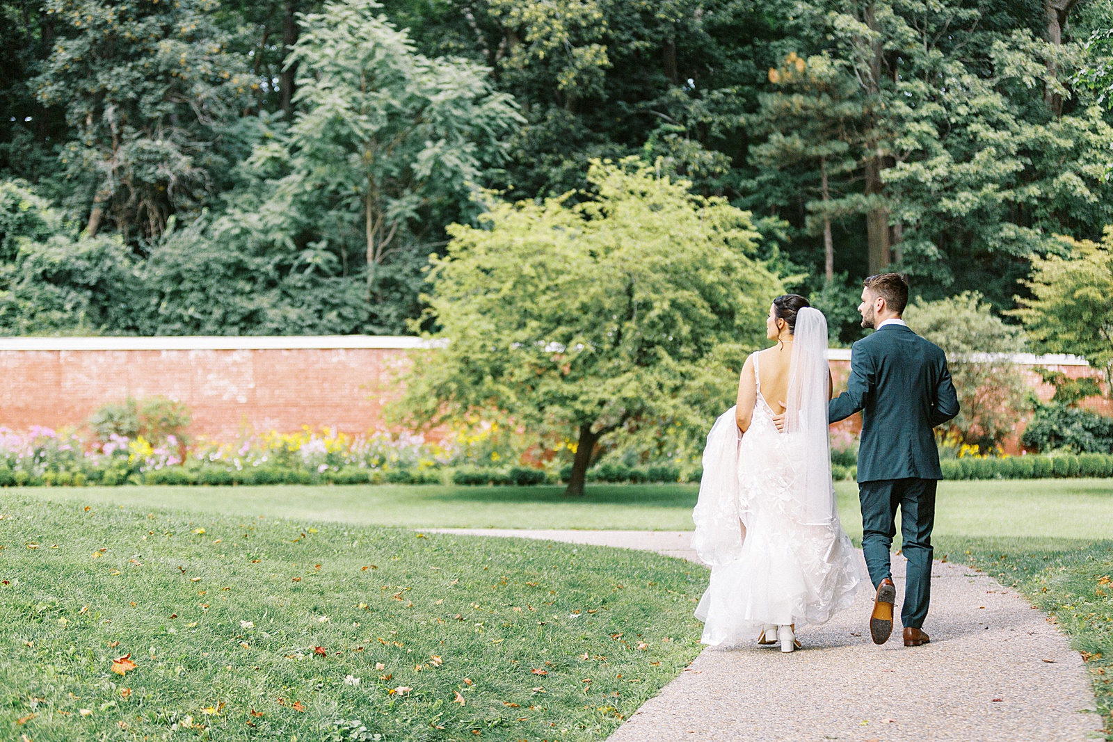 Bride and groom approach ceremony in a garden together.