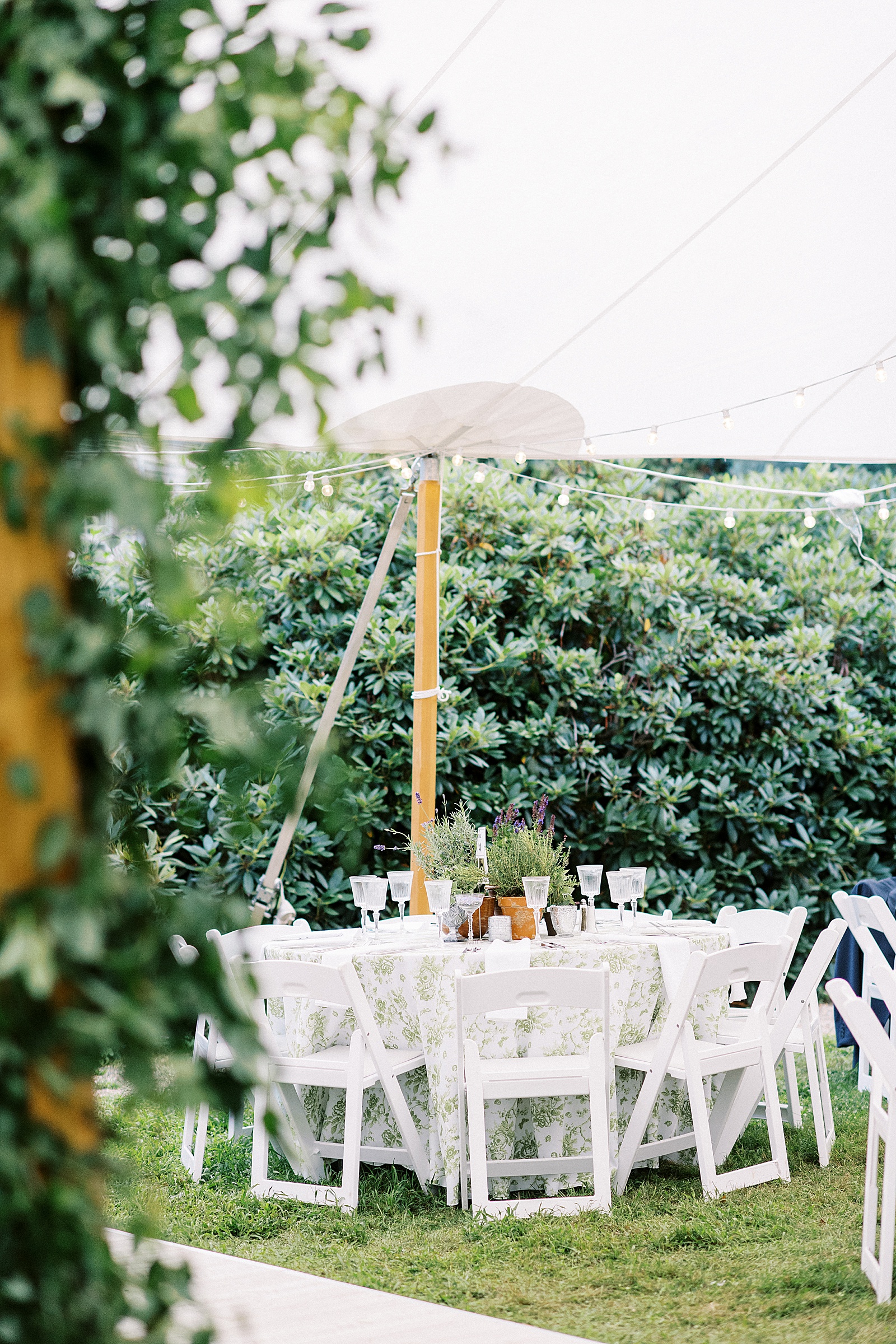 Table at an outdoor tented wedding reception in a garden. 