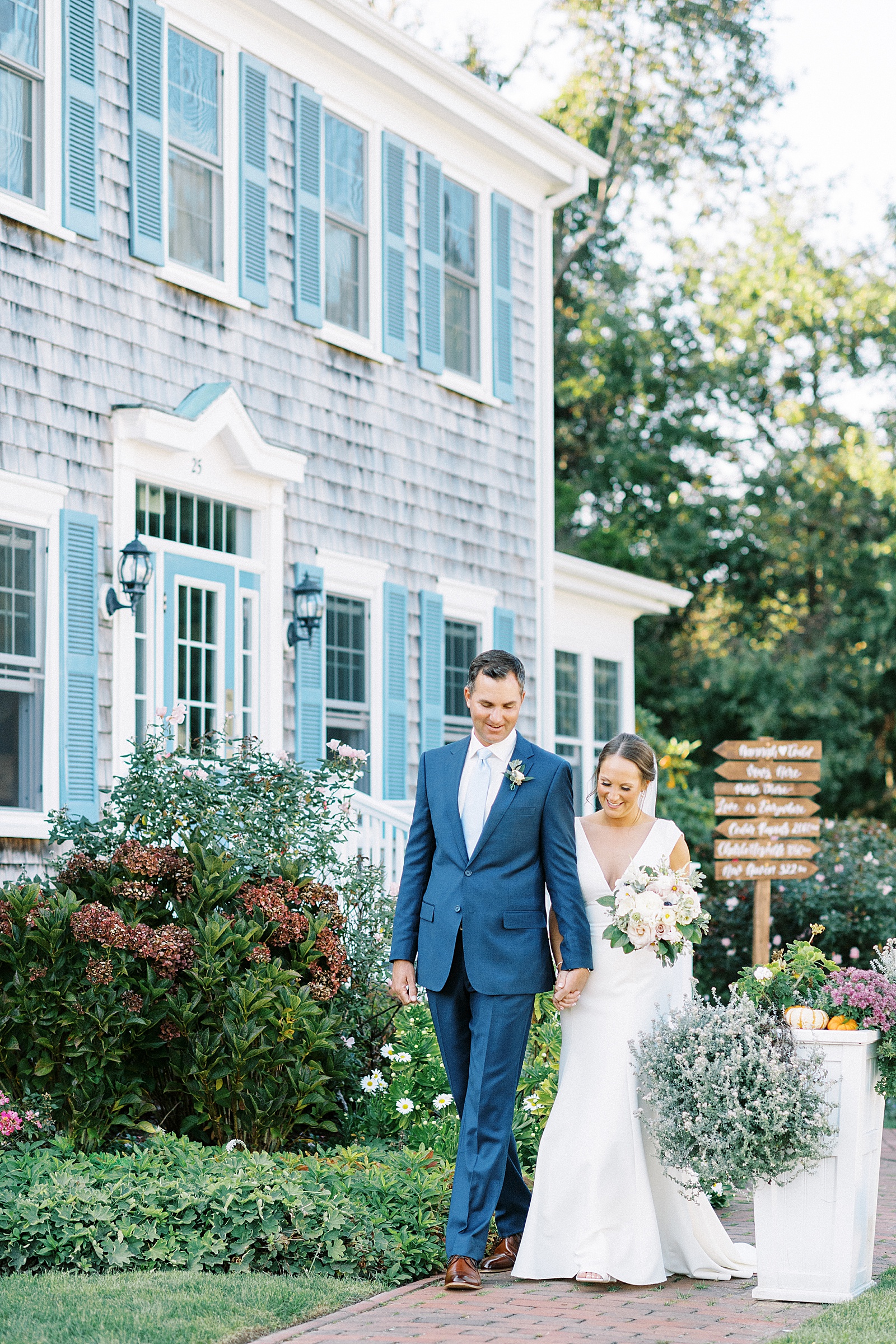 Bride and groom walking in front of Cape Cod house at wedding with Boston Wedding Photographer.