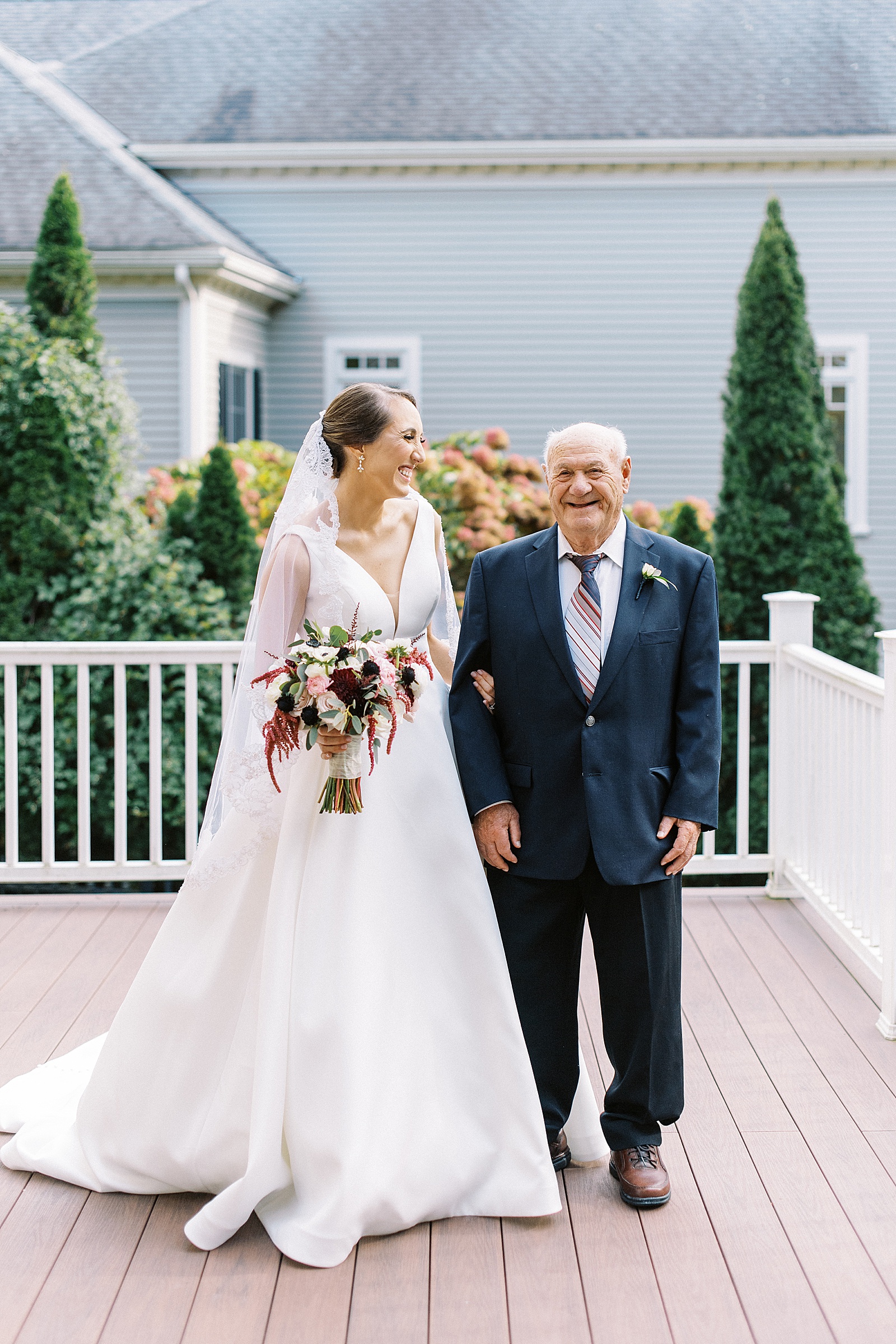 Bride looks lovingly at her grandfather in a suit with a striped tie. 