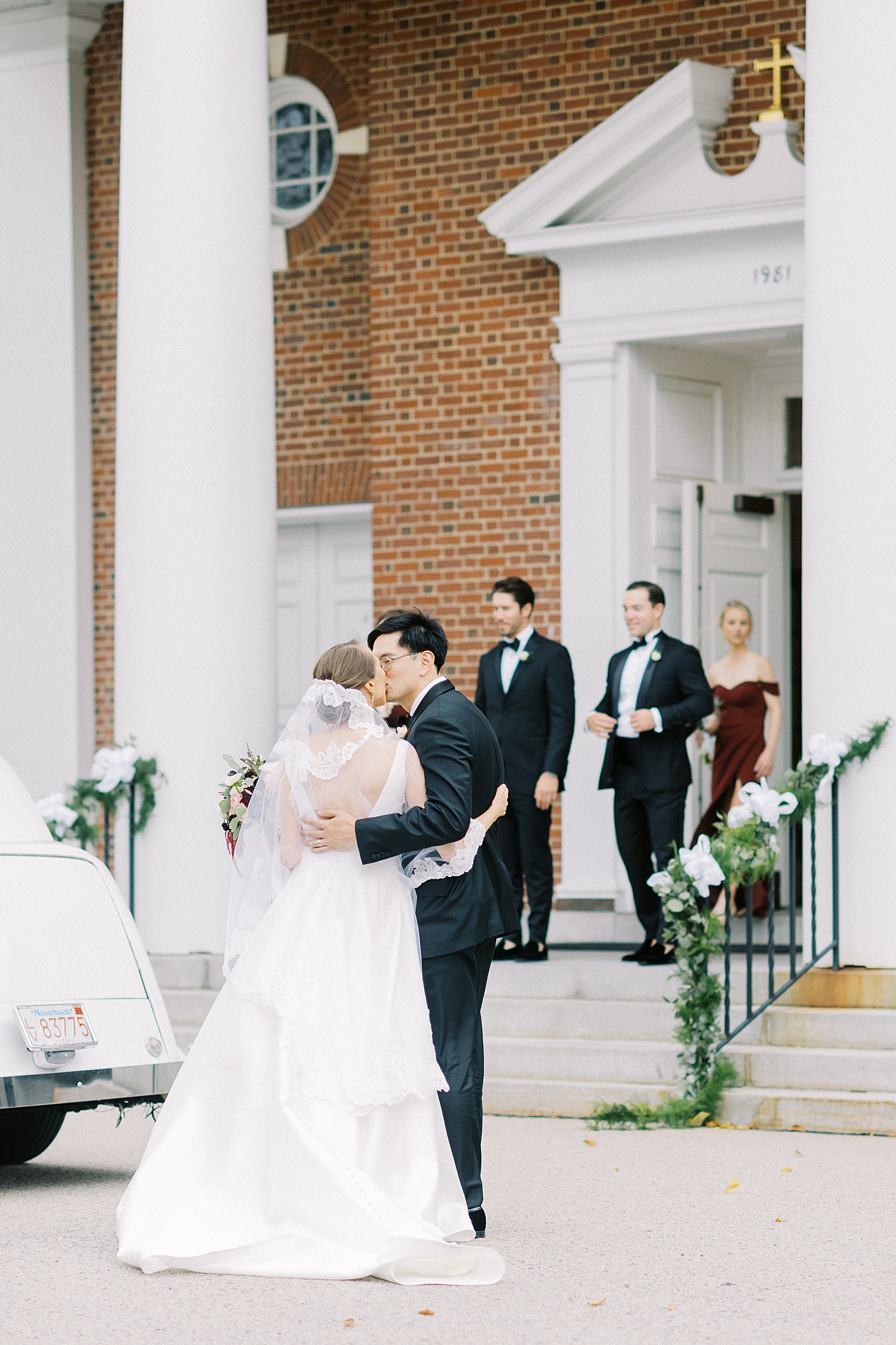 Newlyweds kissing in front of a big old church in Lexington, MA after their wedding ceremony. 