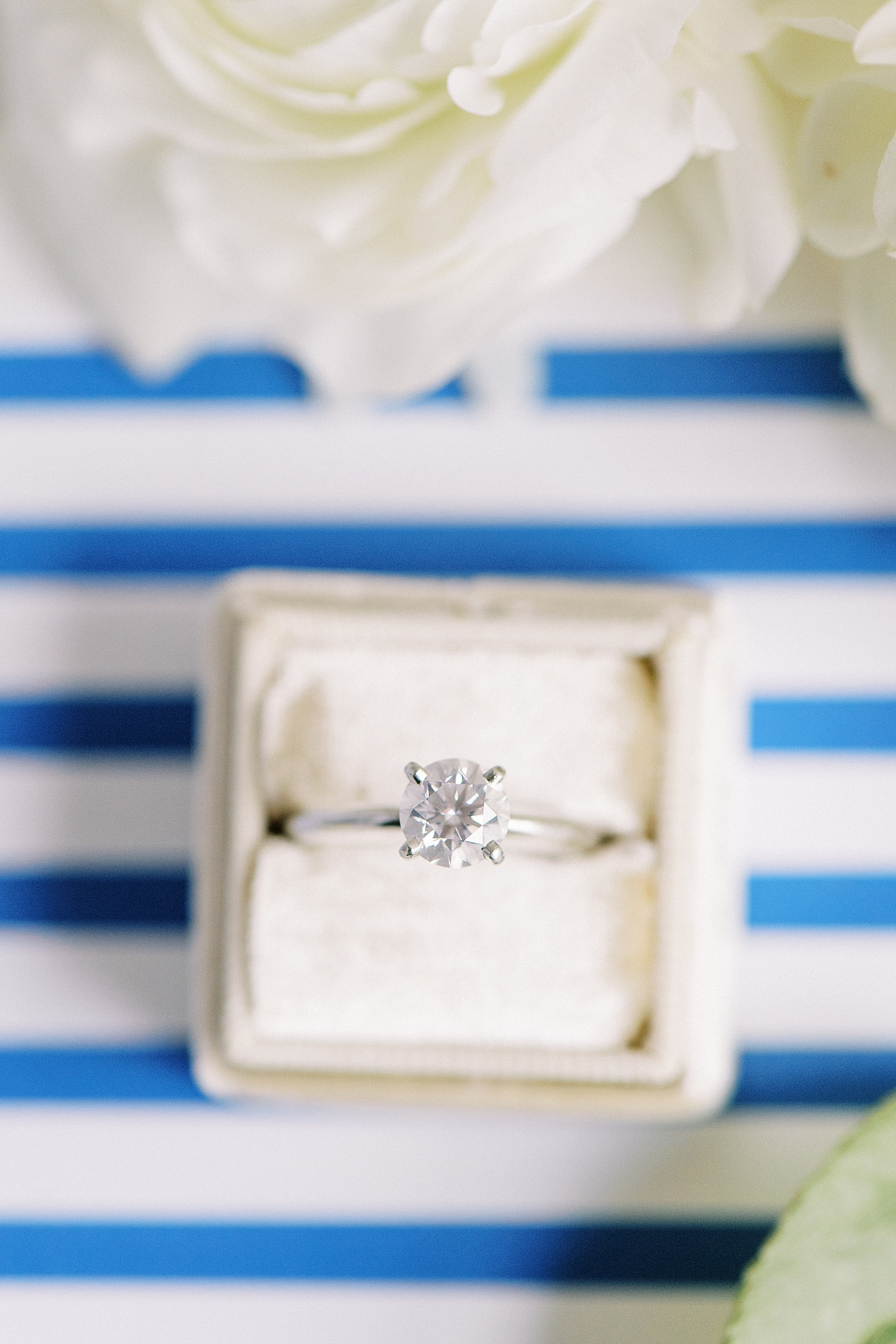 Diamond engagement ring in a white box against blue stripes for a New York Wedding. 