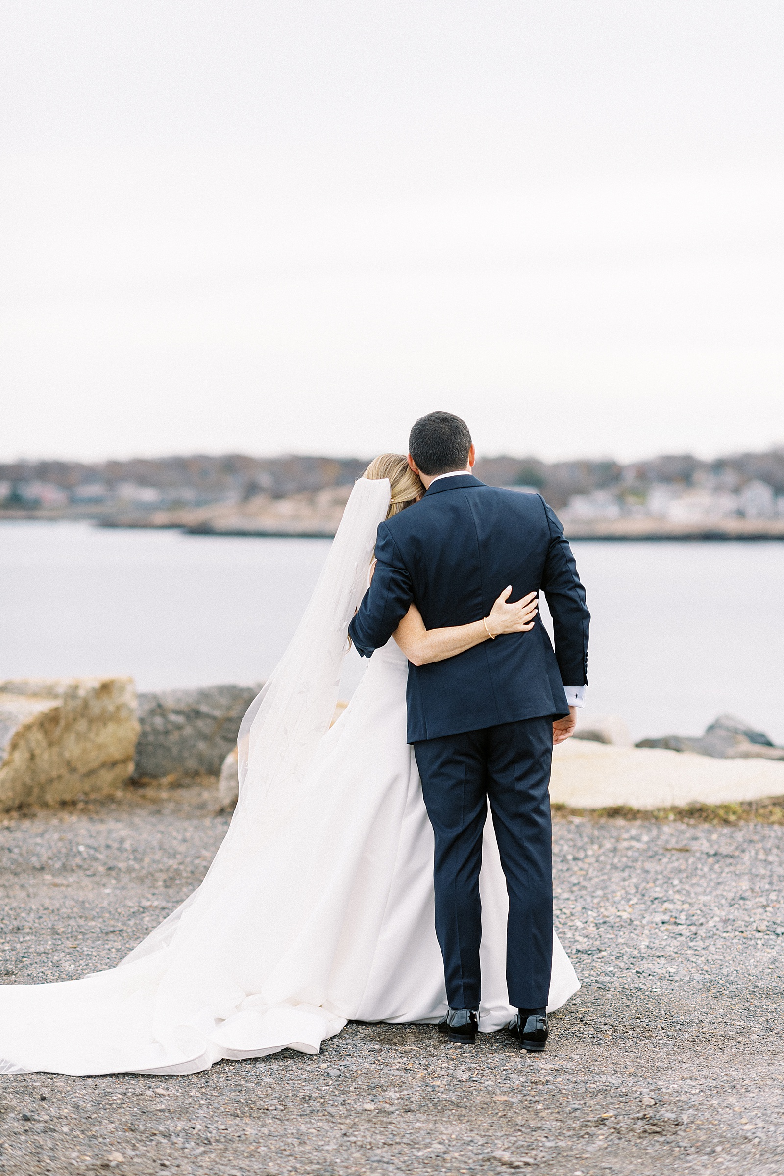 Bride and groom hugging and looking out over the water by New York photographer, Lynne Reznick.