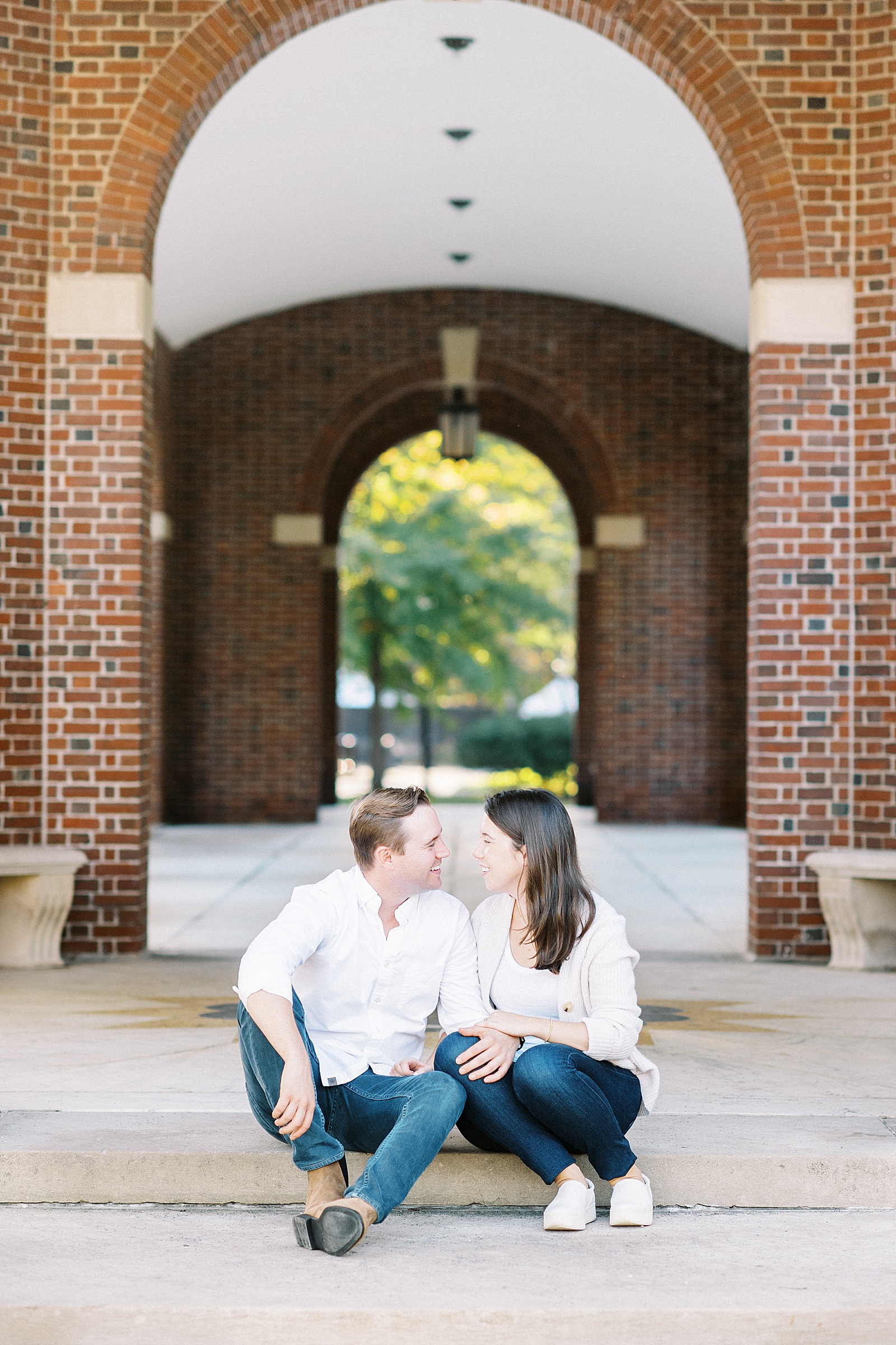 Couple sitting on a step under brick arches for their Saratoga Springs Engagement session