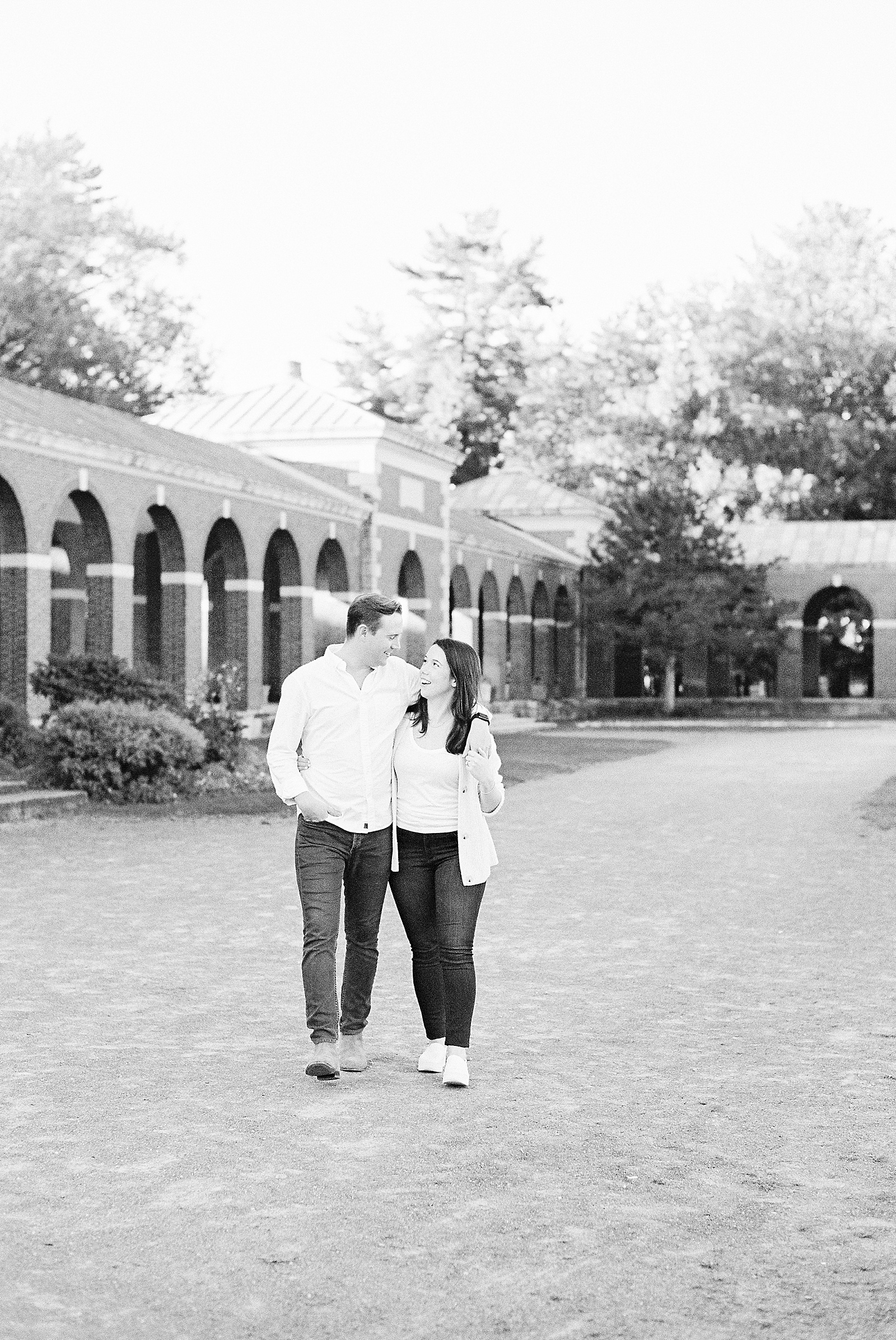 Engaged couple walking on a pathway in front of the Hall of Springs for Saratoga Springs Engagement session 