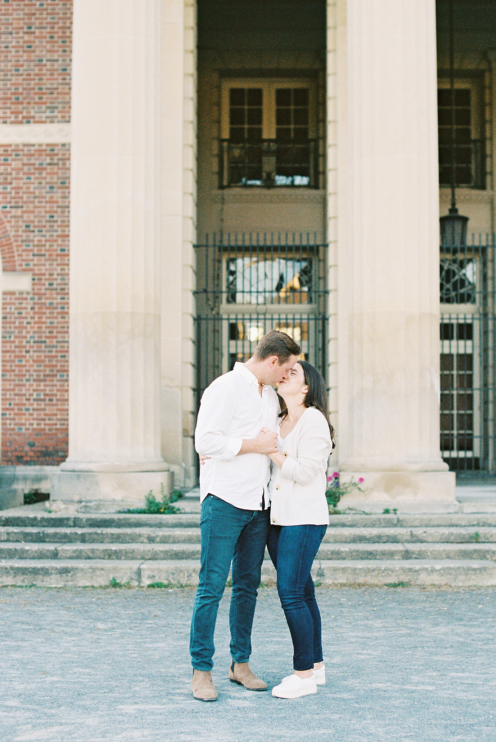 Man and woman in white shirts and jeans kissing in front of an old building in New York 