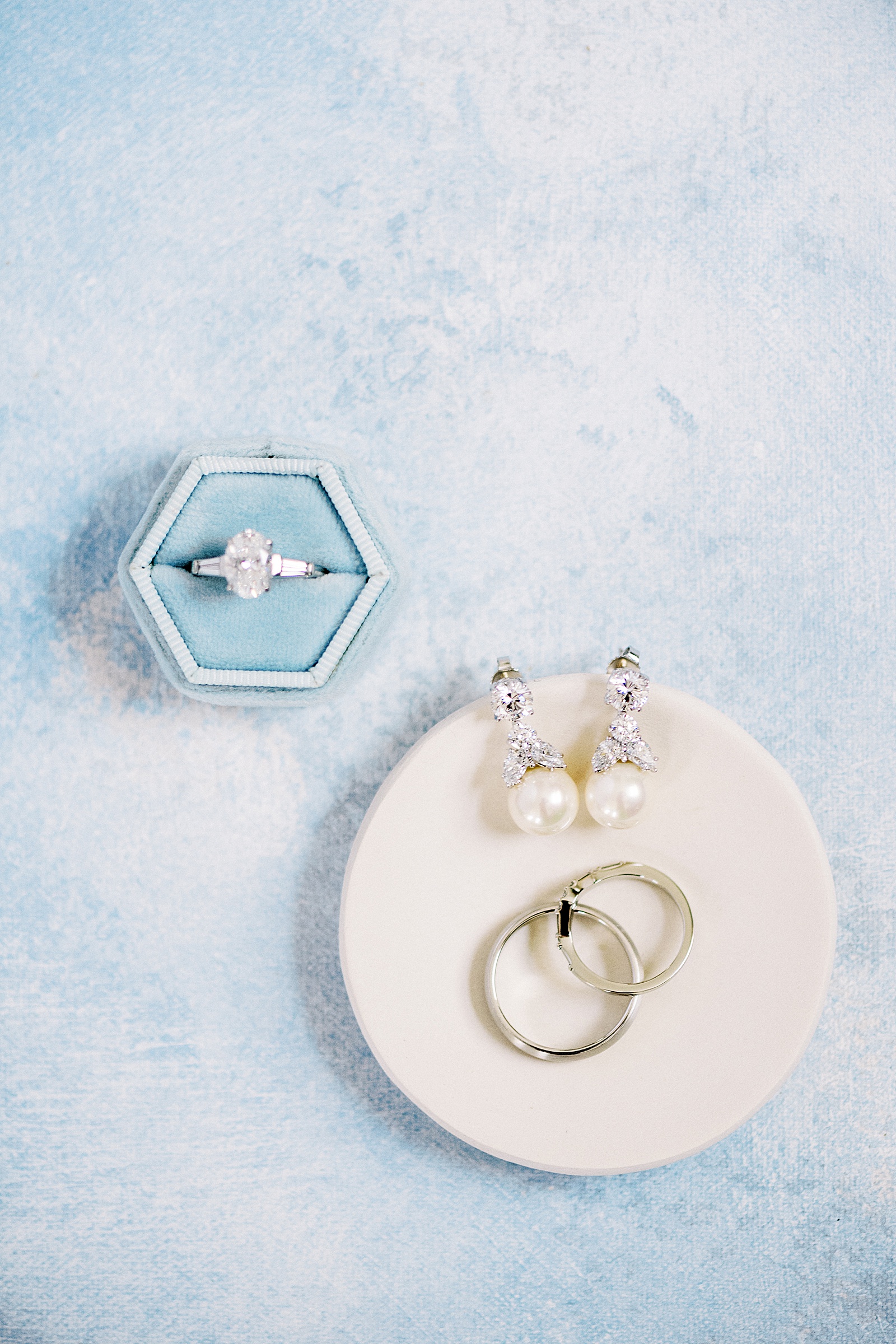 Rings and earrings lying on a blue background for coastal New York wedding