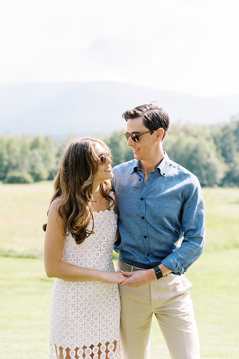 couple in sunglasses embrace in field by Boston wedding photographer