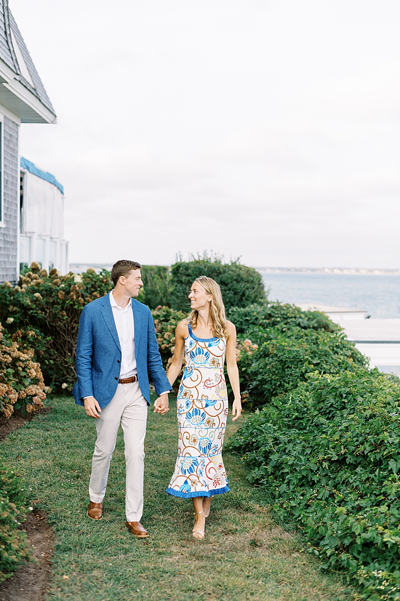 couple in blue walk in garden for rehearsal dinner photography event