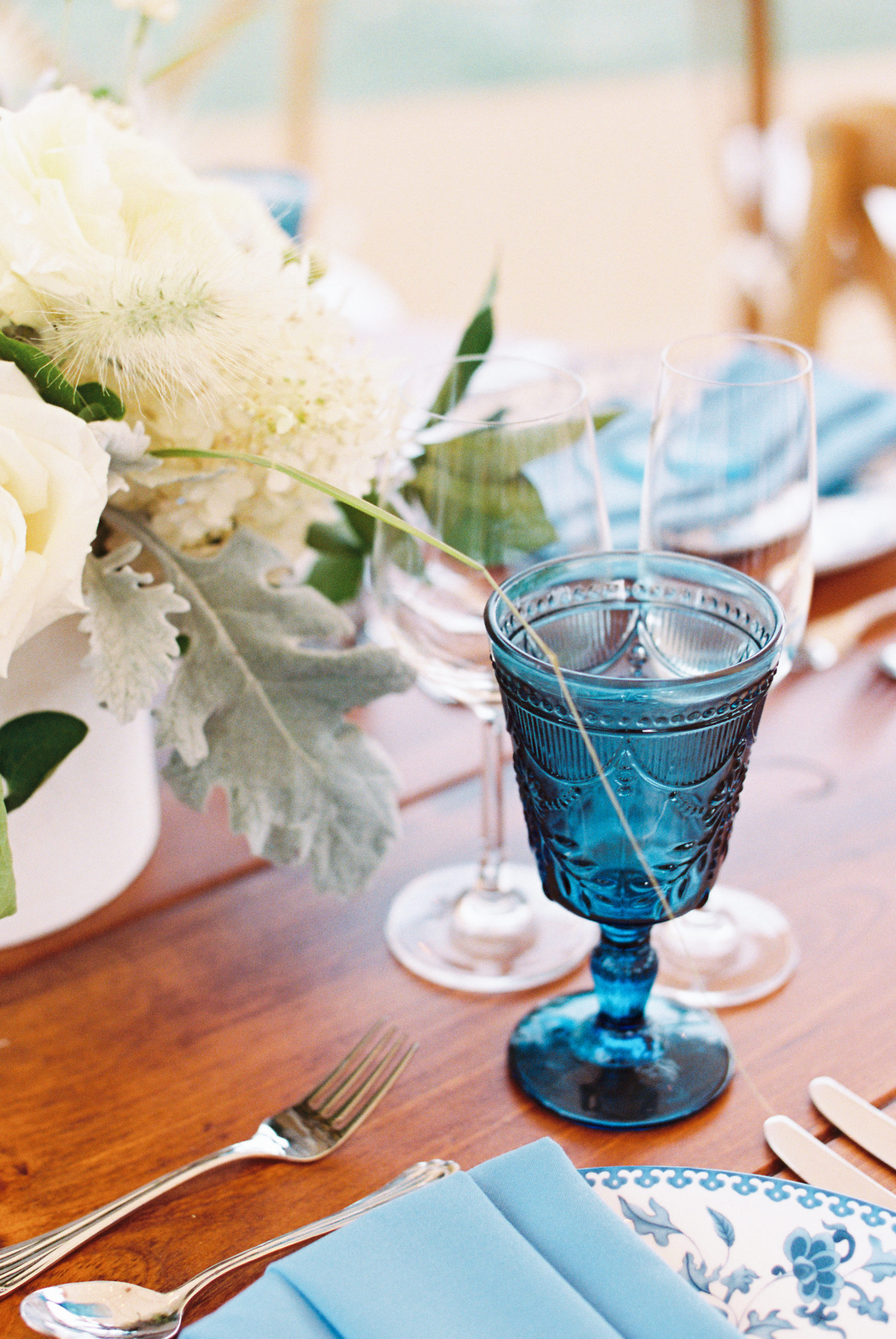 blue glass water goblet set on a table with flowers for post creating your wedding registry