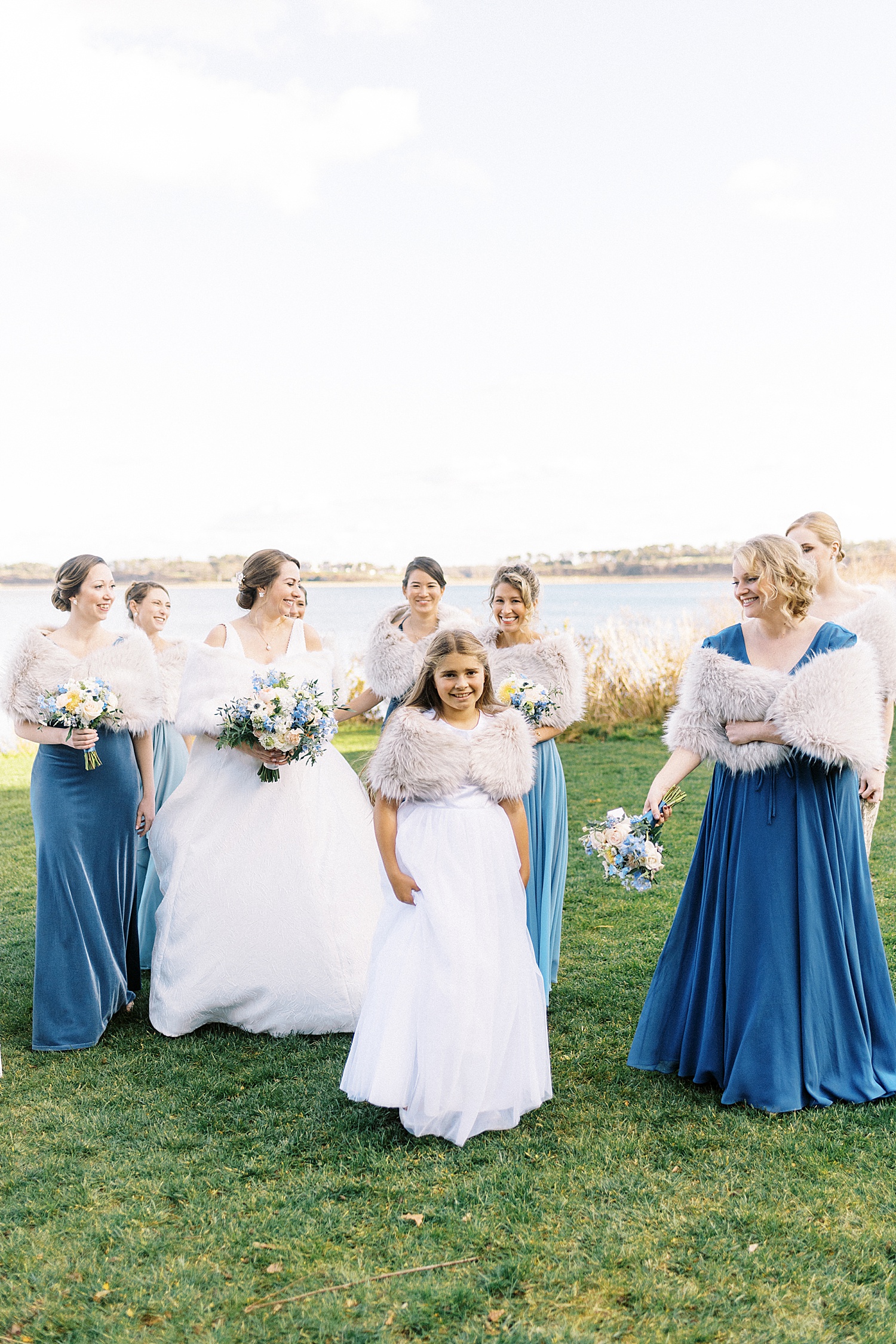 Bridesmaids in blue walking in front of the water in Cape Cod