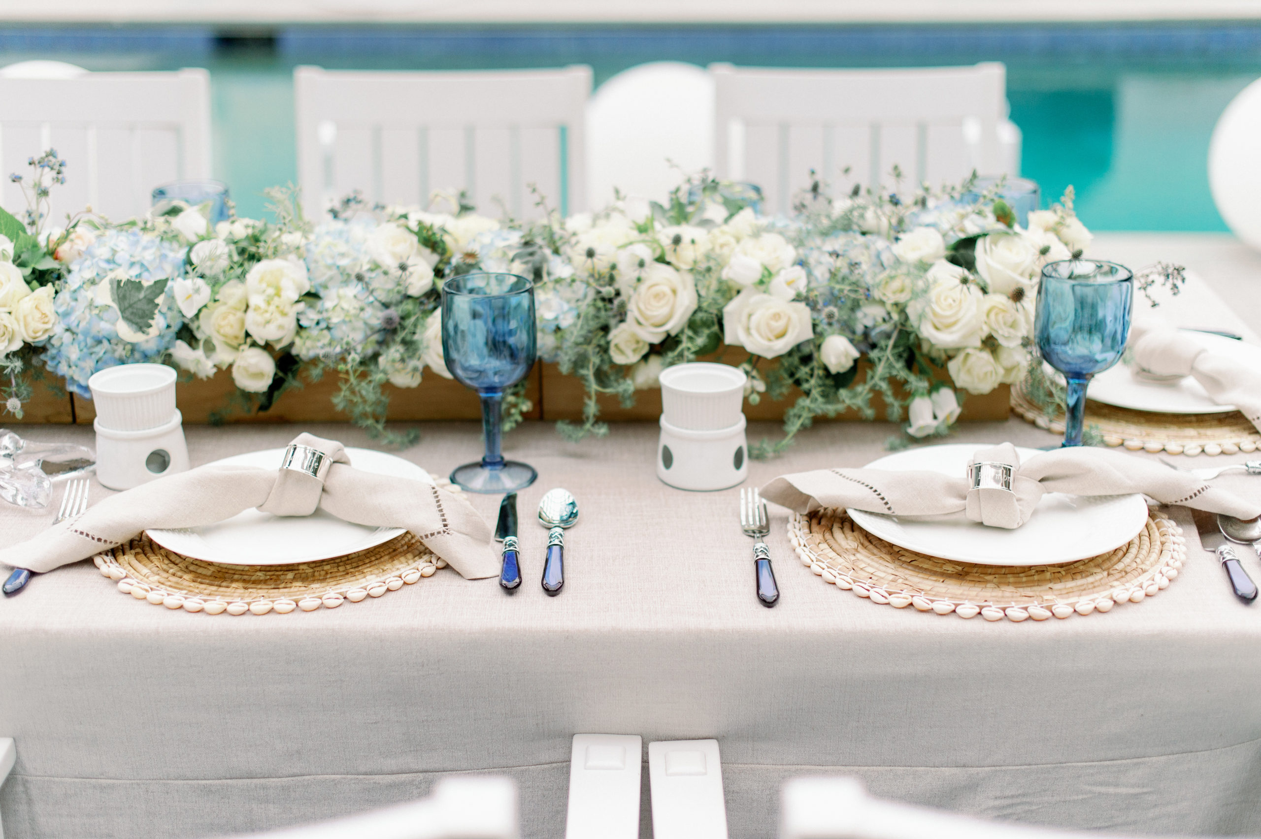 linen tablecloth with floral centerpiece and two place settings with linen napkins and silver napkin holders