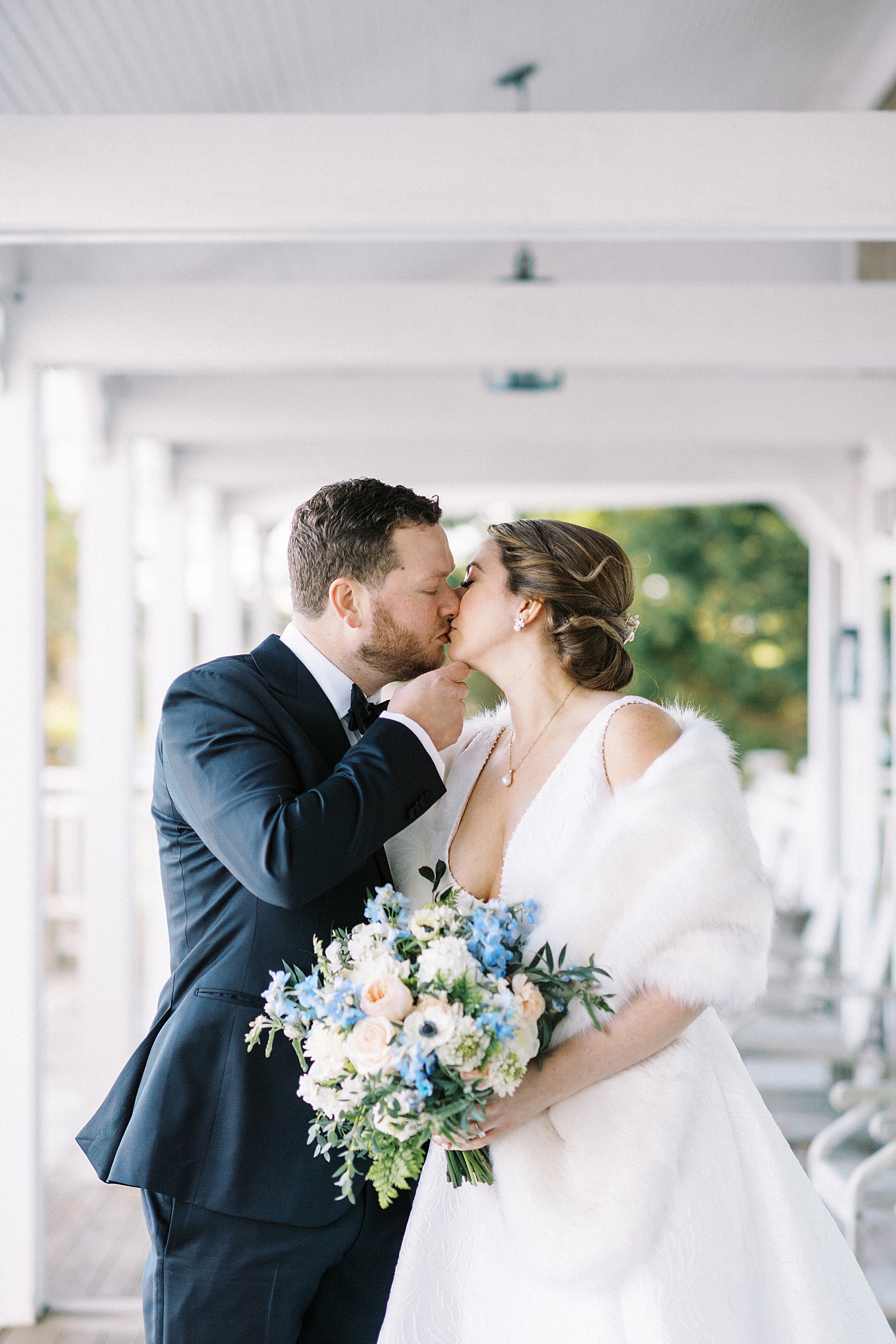 Bride and groom kissing on a large white porch 