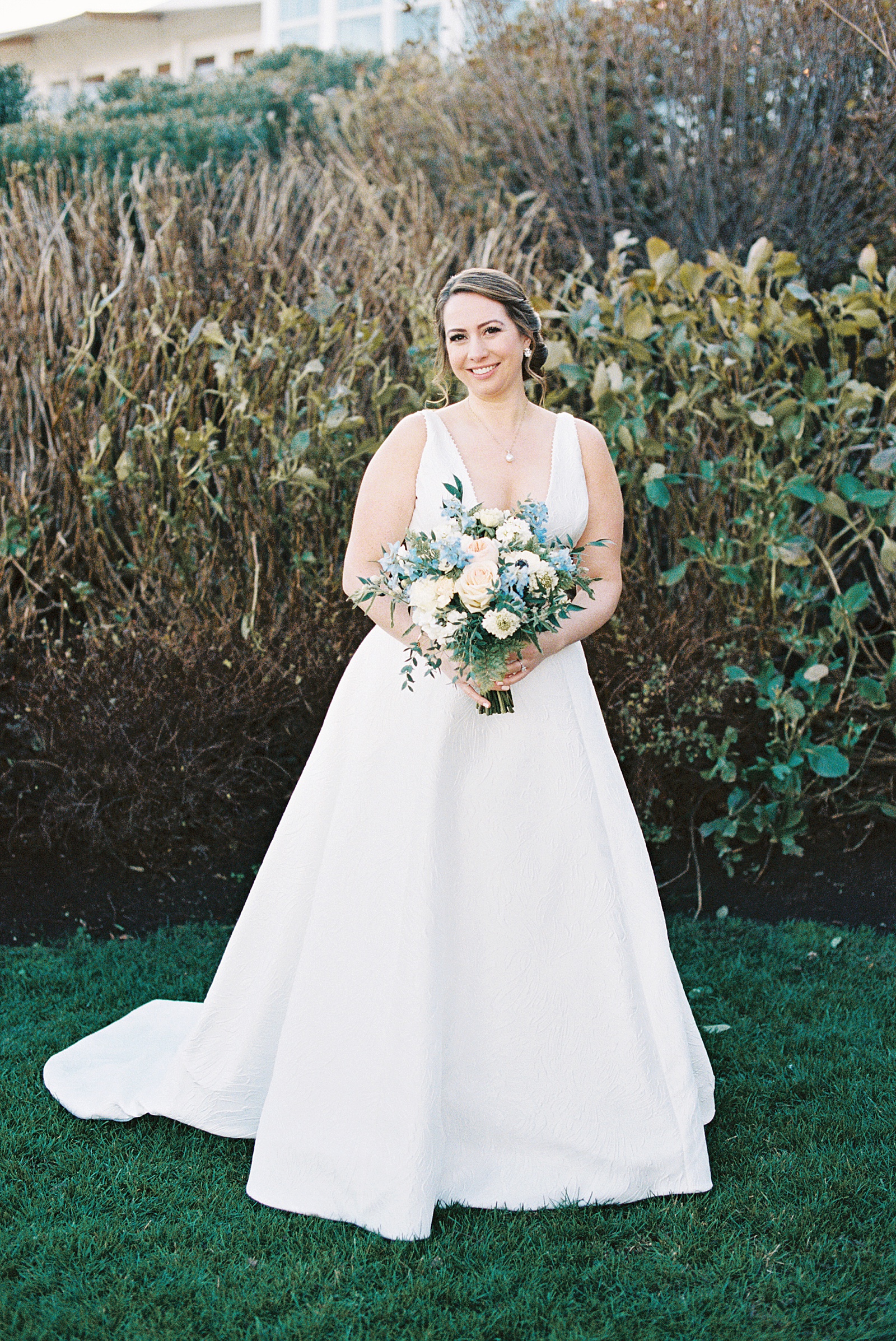 Bride holding large bouquet of cream and blue flowers 