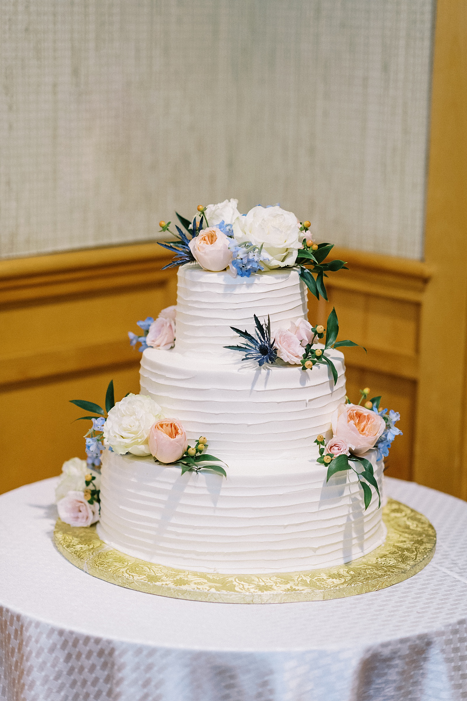 Three tier white cake with peach and blue flowers