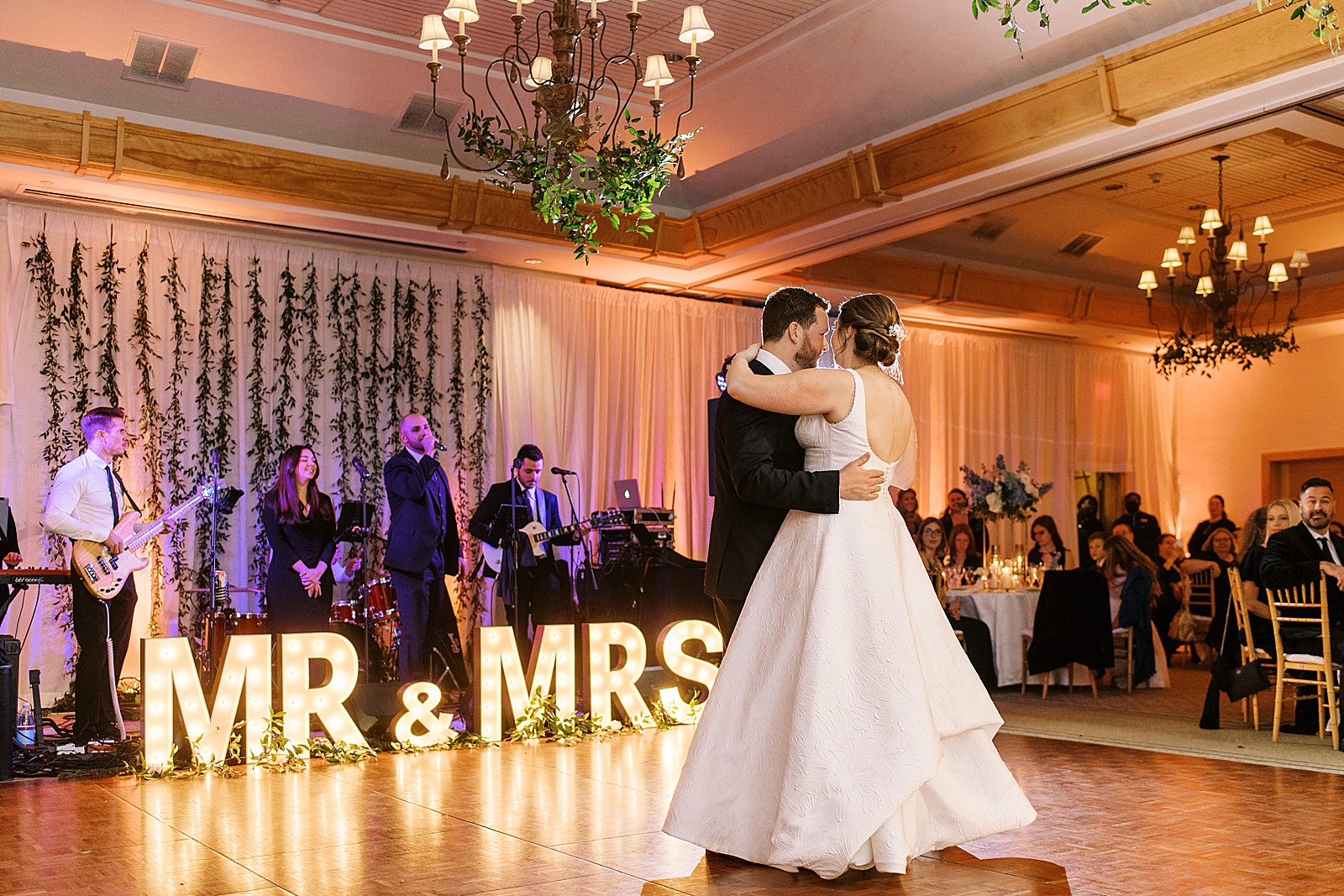 Bride and groom sharing a first dance in front of neon signs
