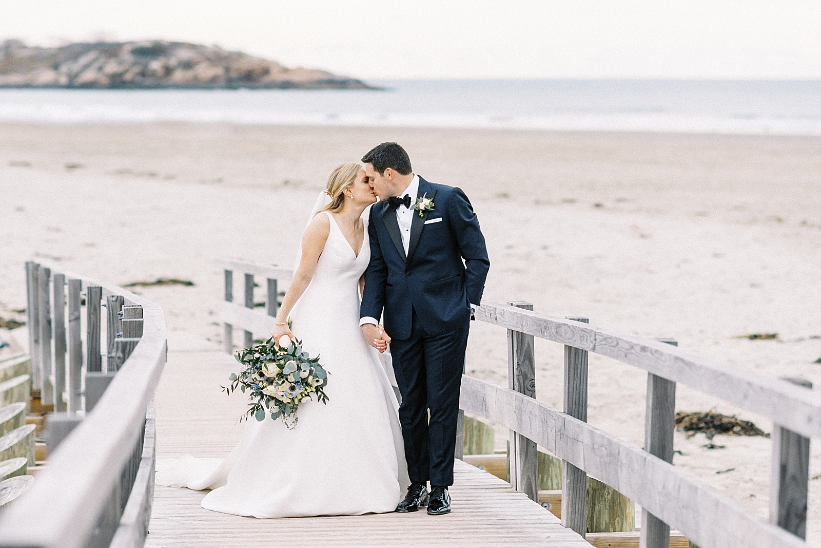Wedding couple kissing on a pier by New England wedding photographer Lynne Reznick