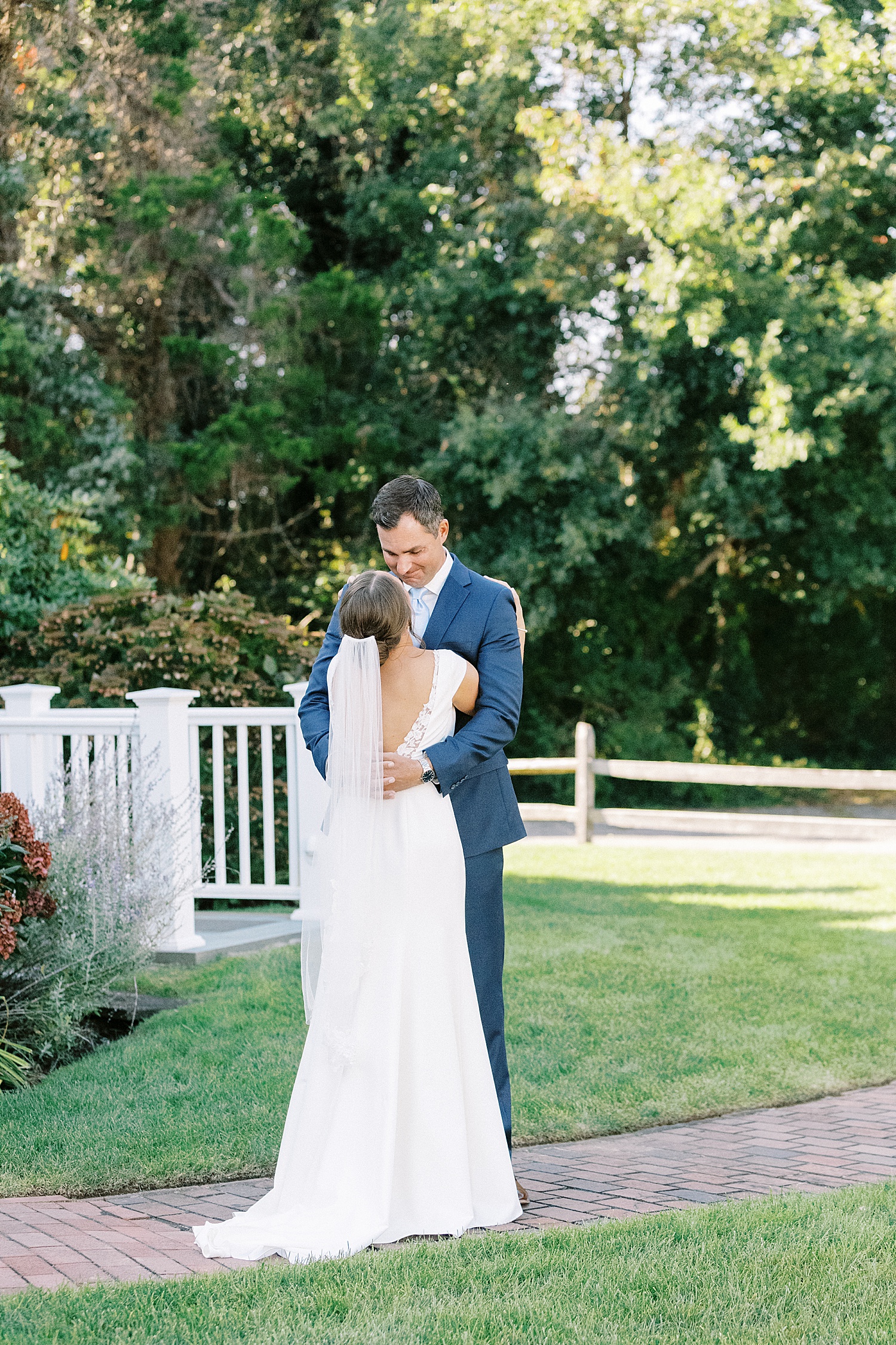 Bride and groom embracing on a lawn in front of their venue 