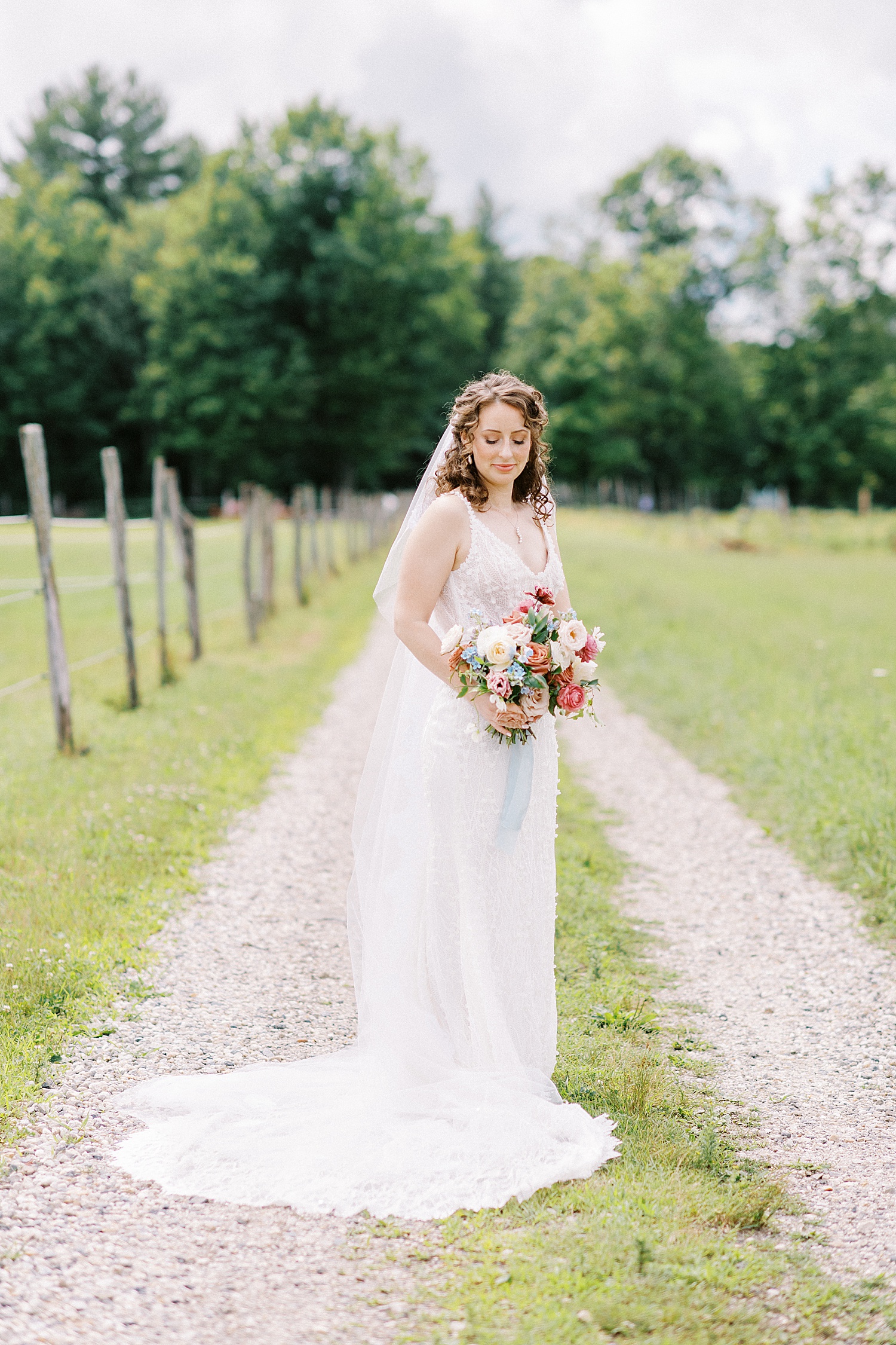 Bride in lace gown with pretty florals in a field for Valley View Farm wedding