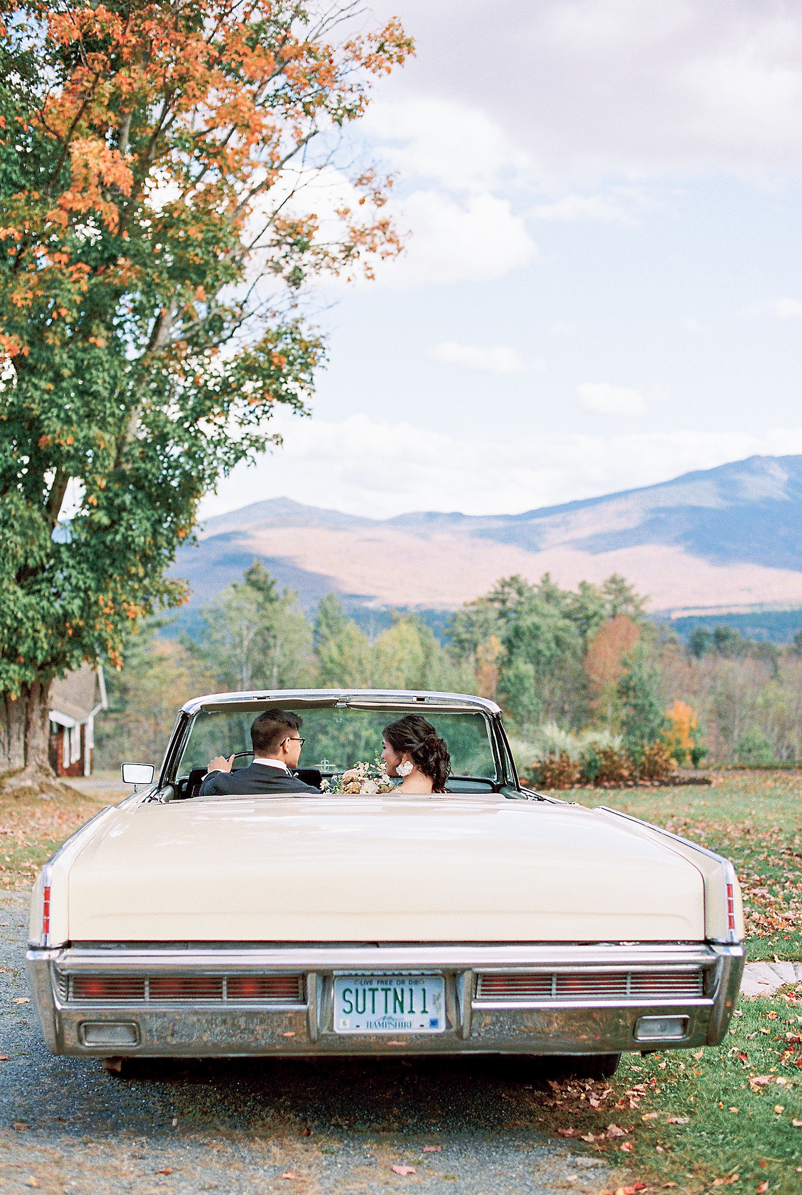 Couple sitting in old times car in front of the mountains by Lynne Reznick Photography 