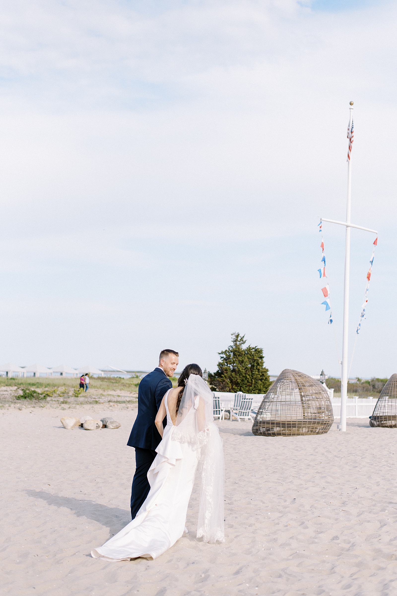 Bride and groom walking across the beach by photographer who talks about wedding expo essentials for the best ROI