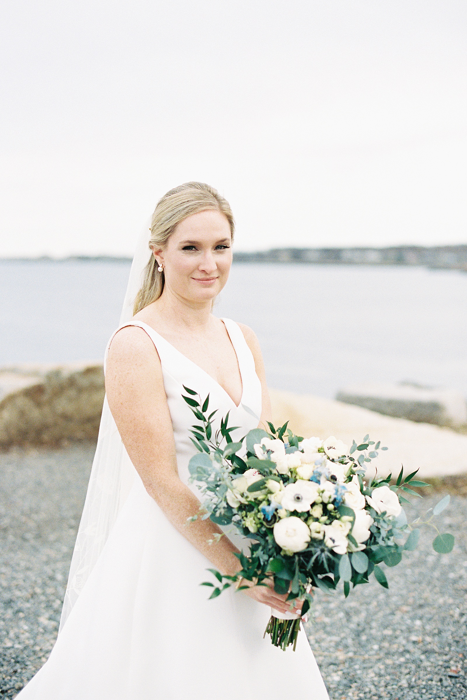 Blonde bride with neutral bouquet in front of the water by Massachusetts wedding photographer