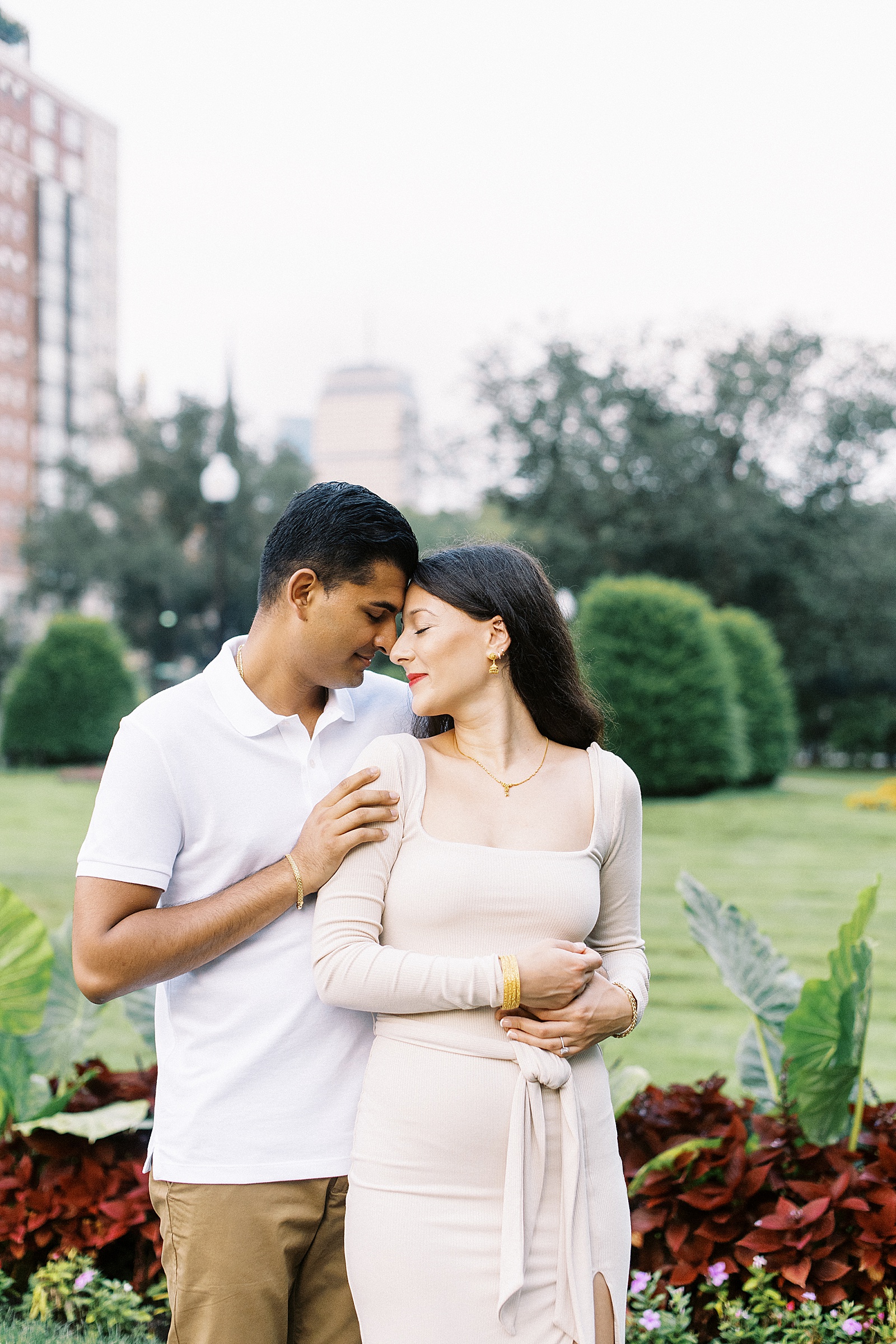 Engaged couple cuddling in field at public garden engagement session
