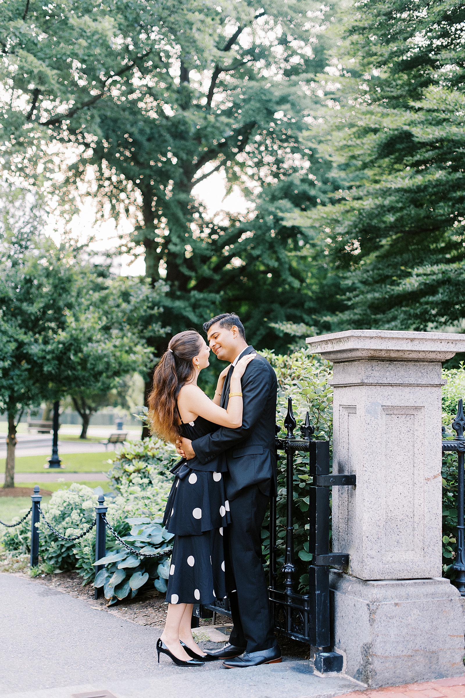Man and woman in formal wear about to kiss at public garden engagement session